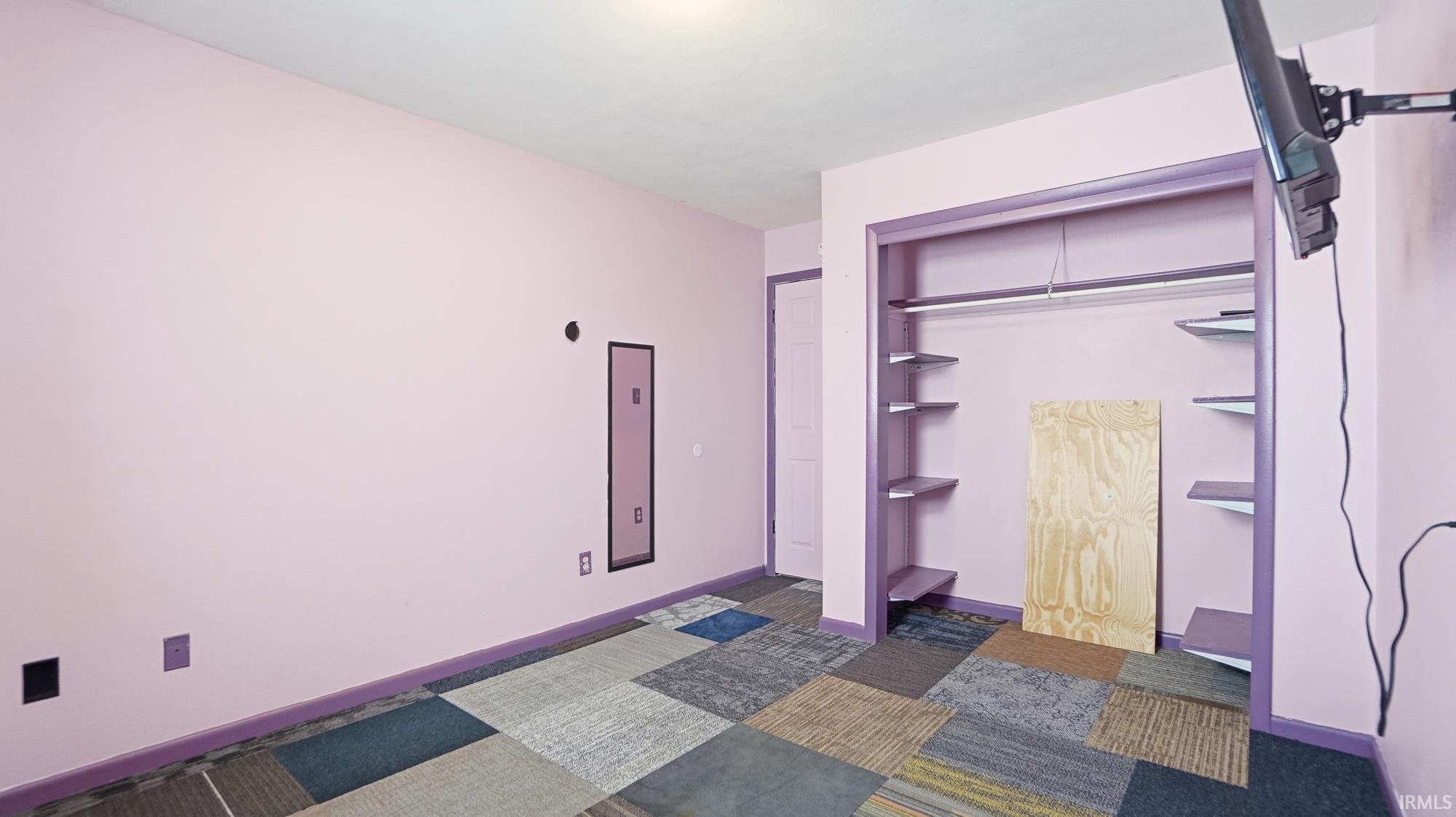 Laundry area with dark carpet and baseboards