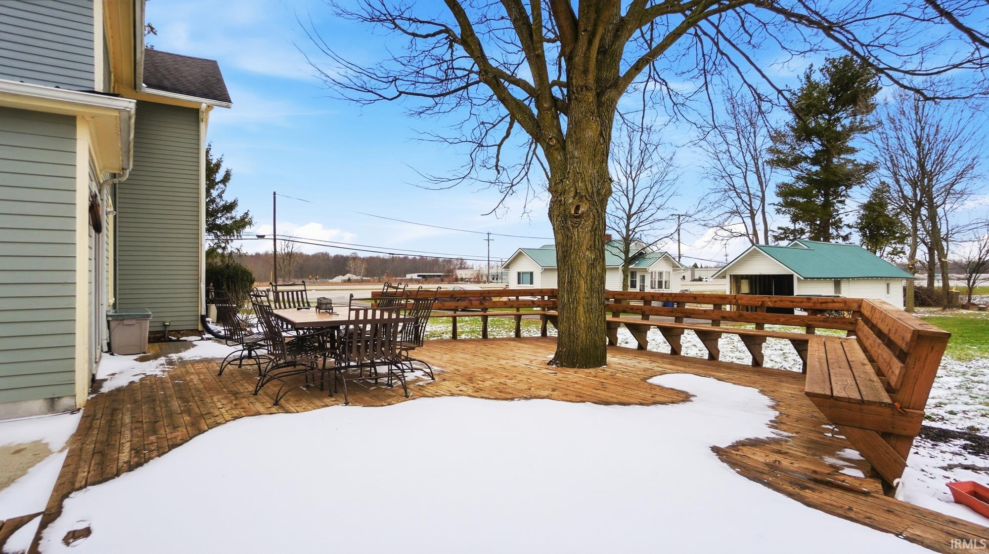 Snowy yard with outdoor dining area and a deck