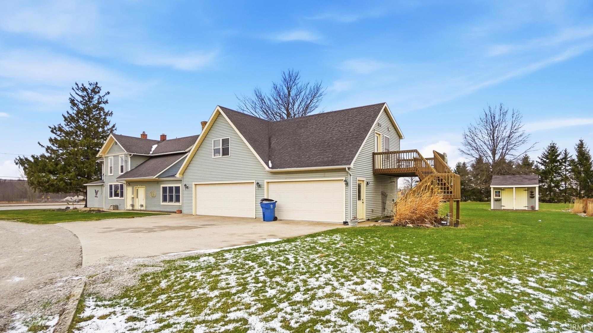 View of home's exterior with concrete driveway, roof with shingles, a yard, a garage, and a storage shed