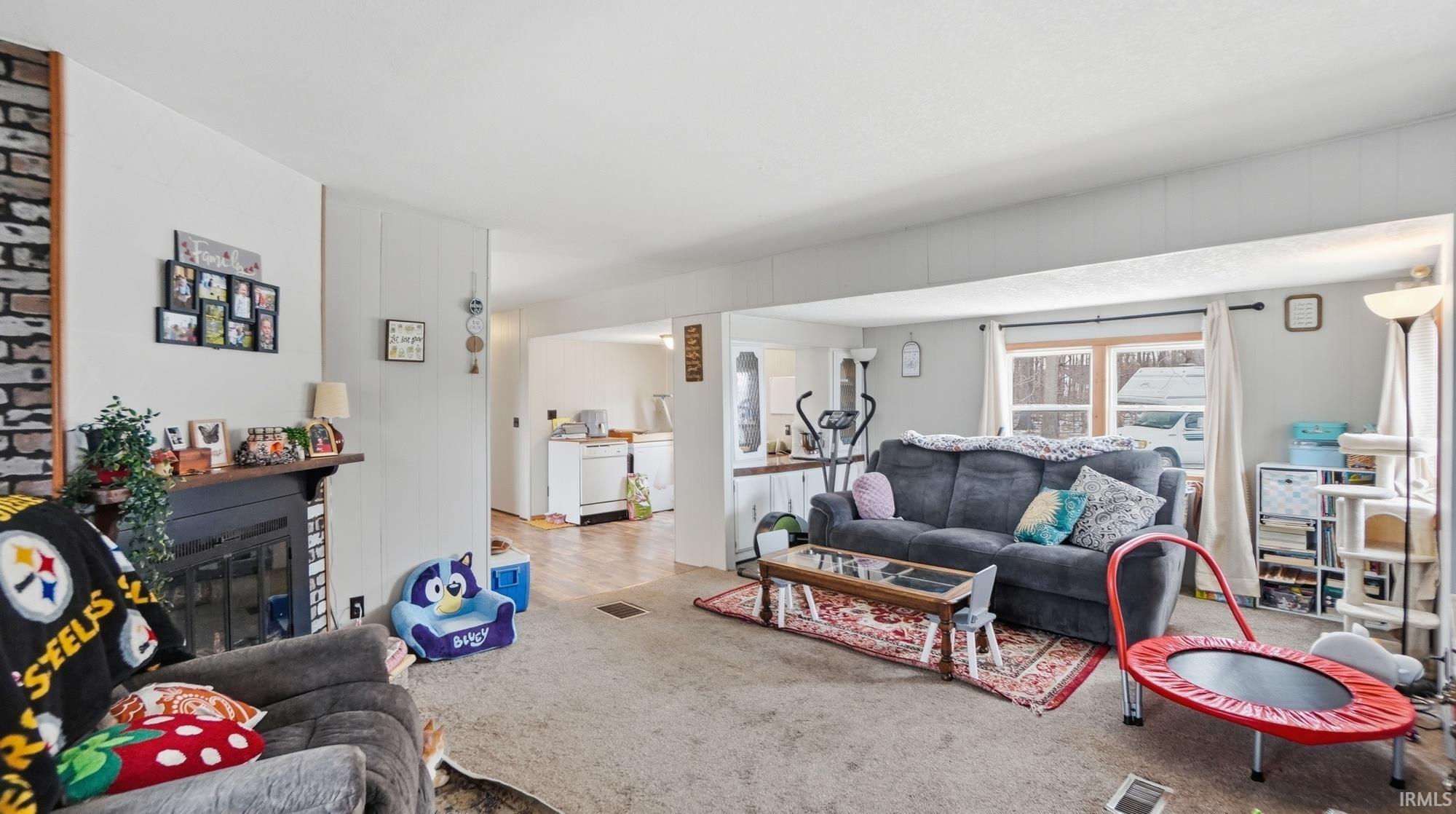 Carpeted living area with a glass covered fireplace
