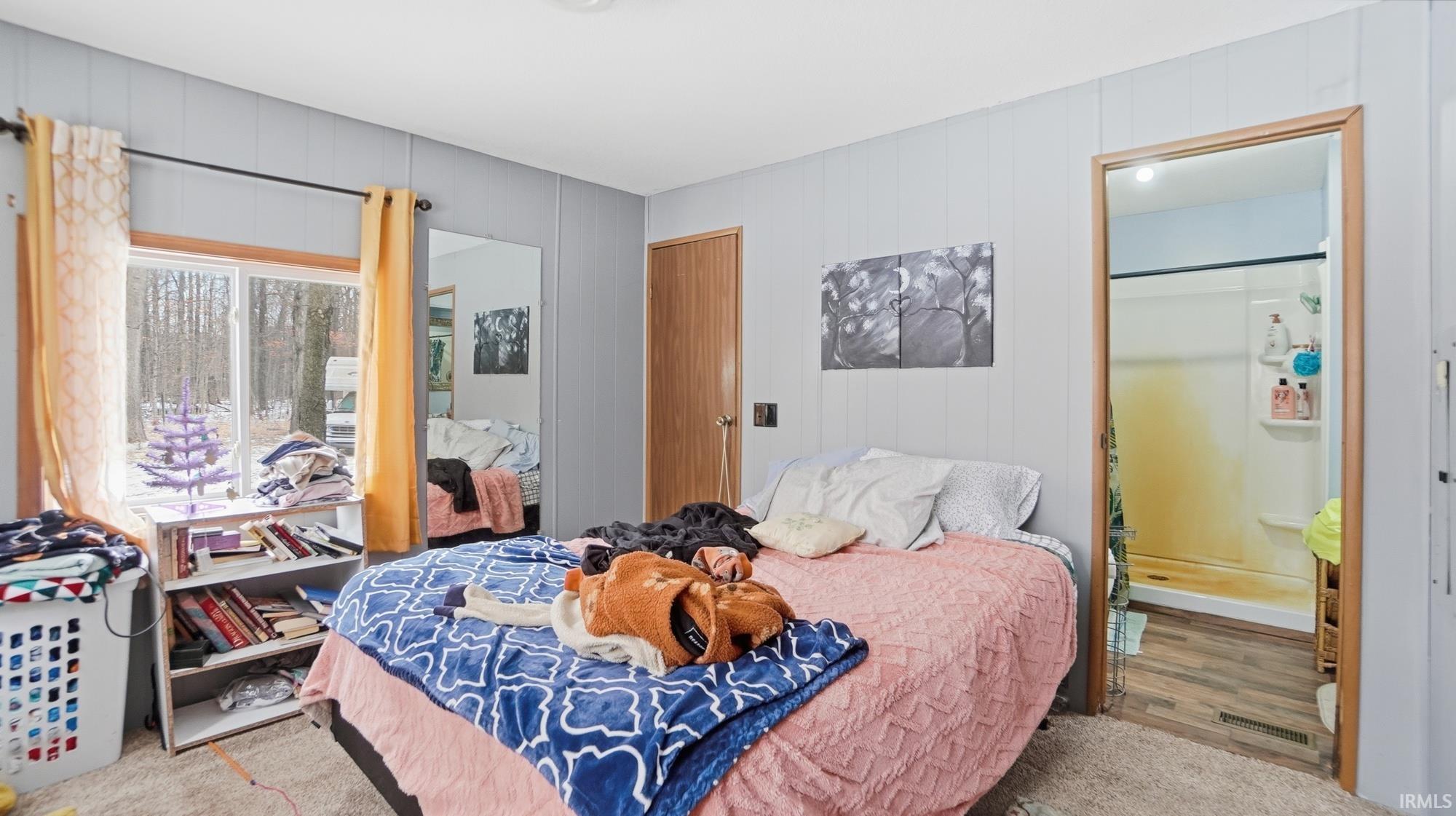 Bedroom with light wood-type flooring and wooden walls