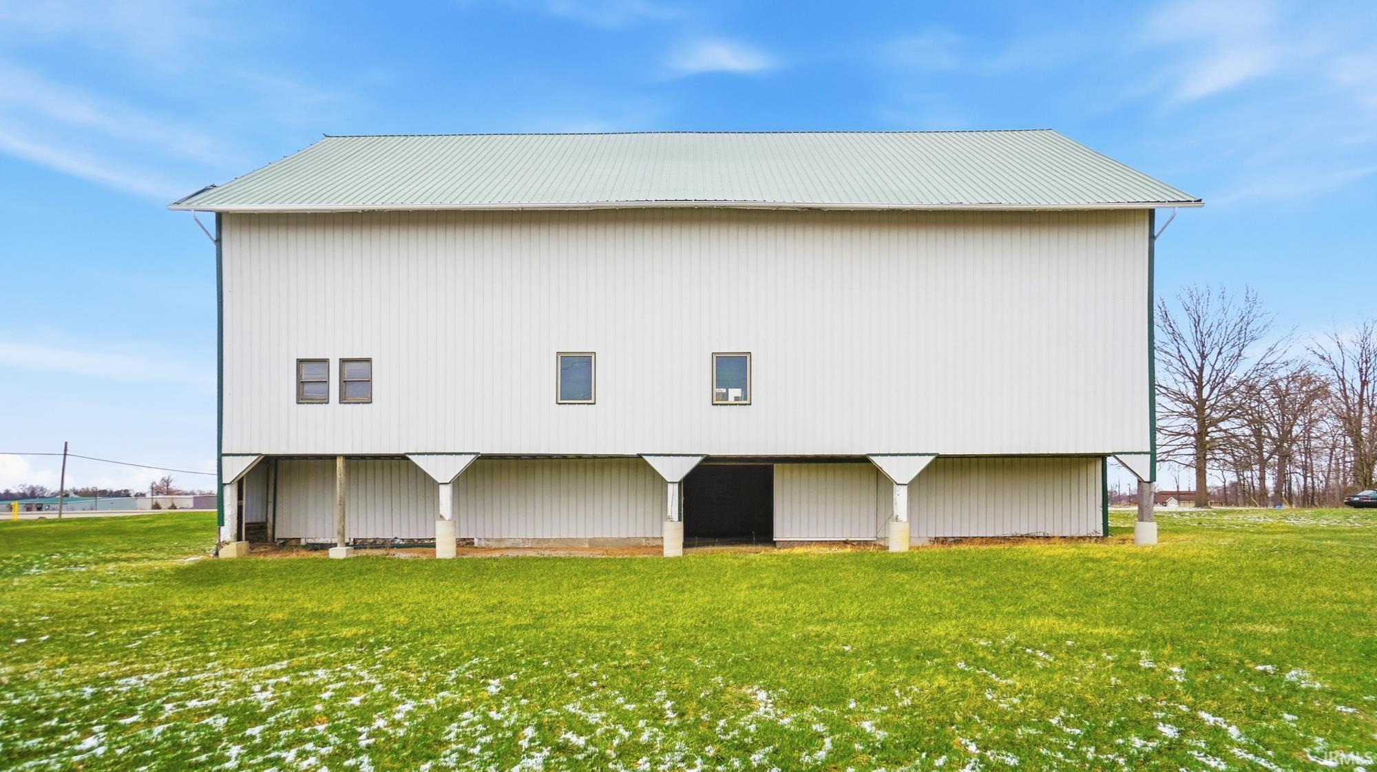 Rear view of property featuring a metal roof, a yard, a pole building, and an outbuilding
