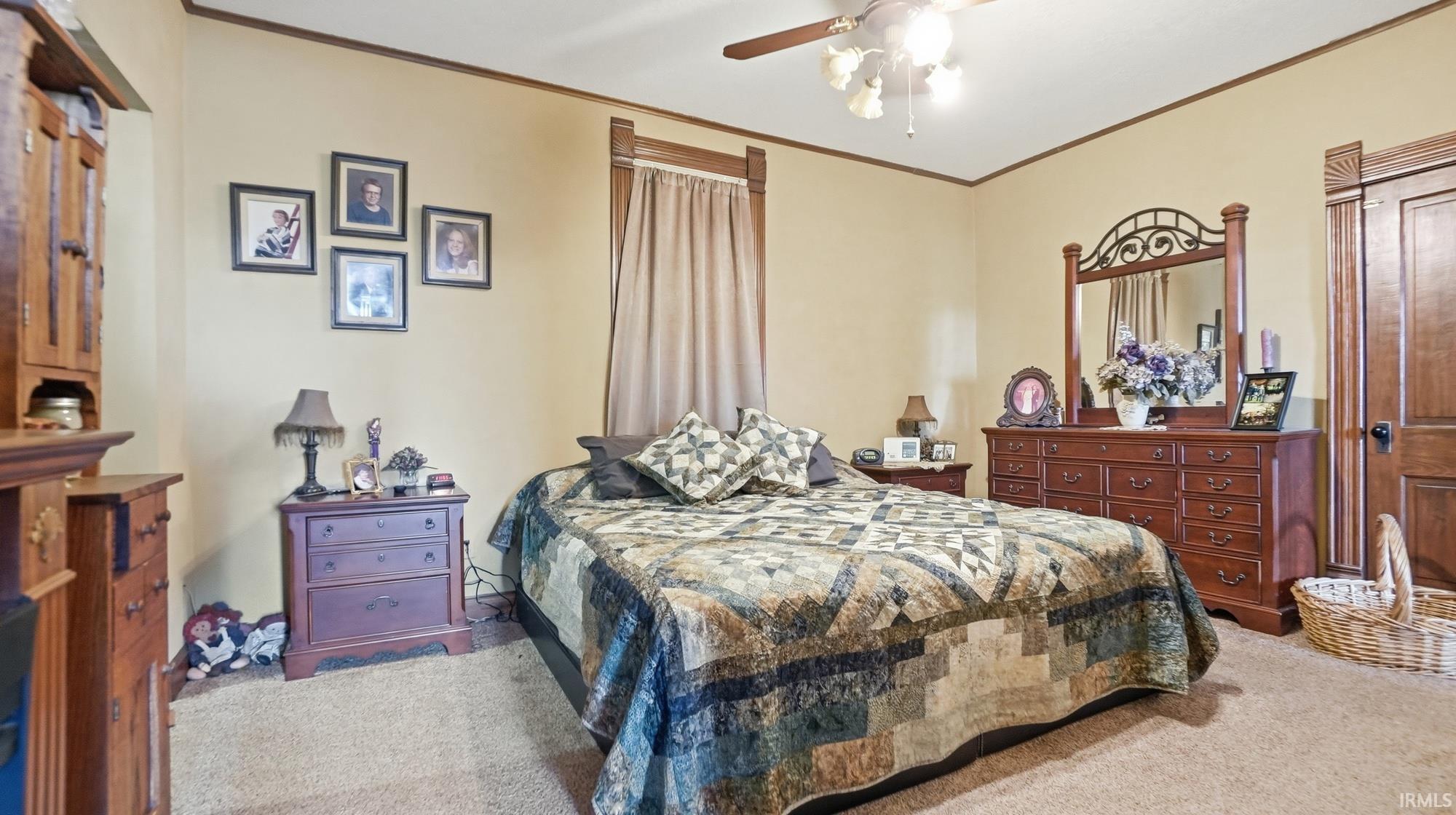 Carpeted bedroom featuring ceiling fan and crown molding