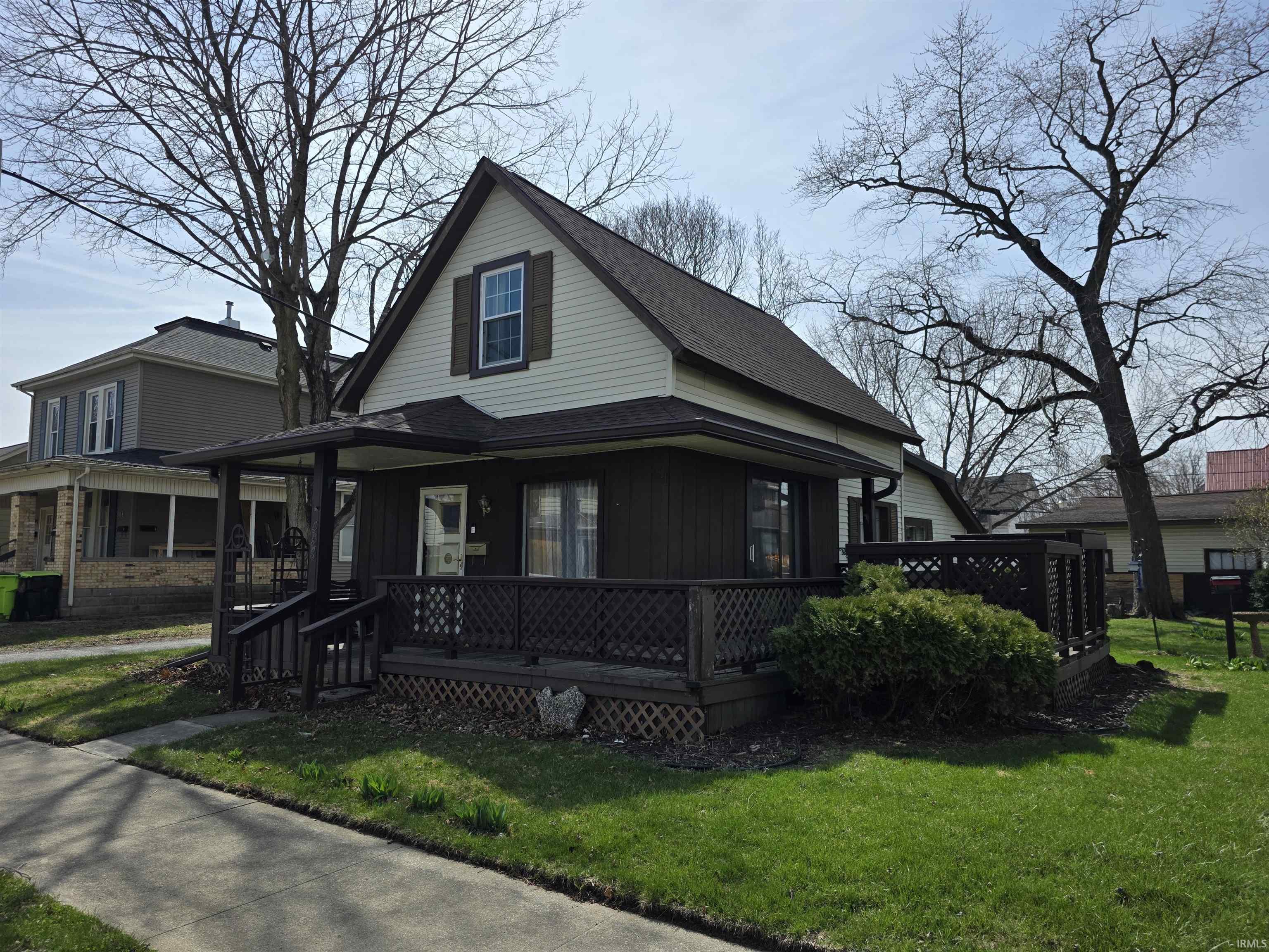 View of front of home with a shingled roof, a front lawn, and covered porch