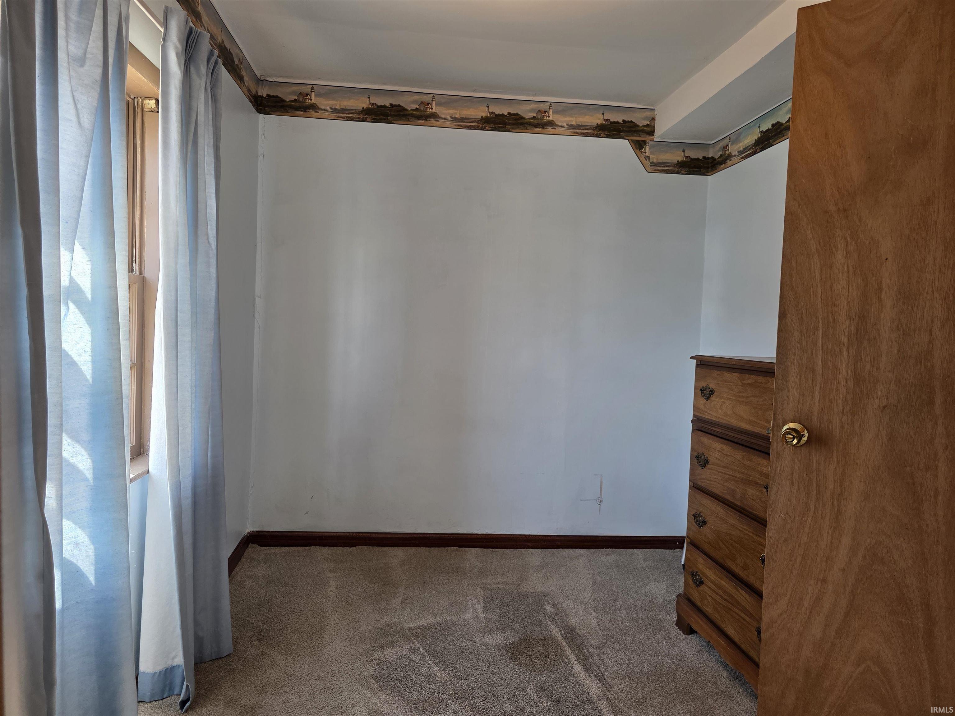 Spare room with dark carpet and baseboards