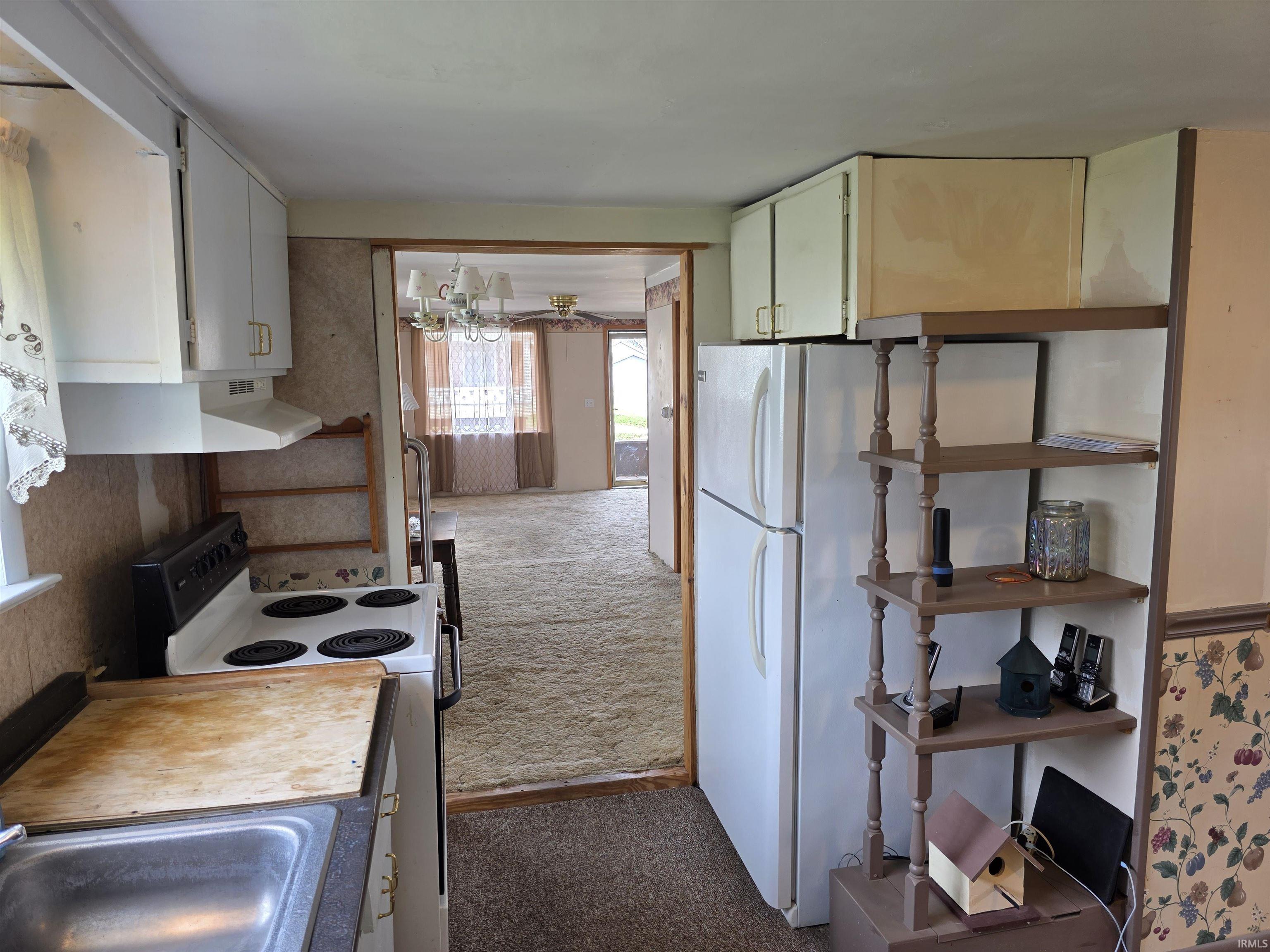 Kitchen featuring range with electric stovetop, light countertops, dark carpet, a chandelier, and freestanding refrigerator