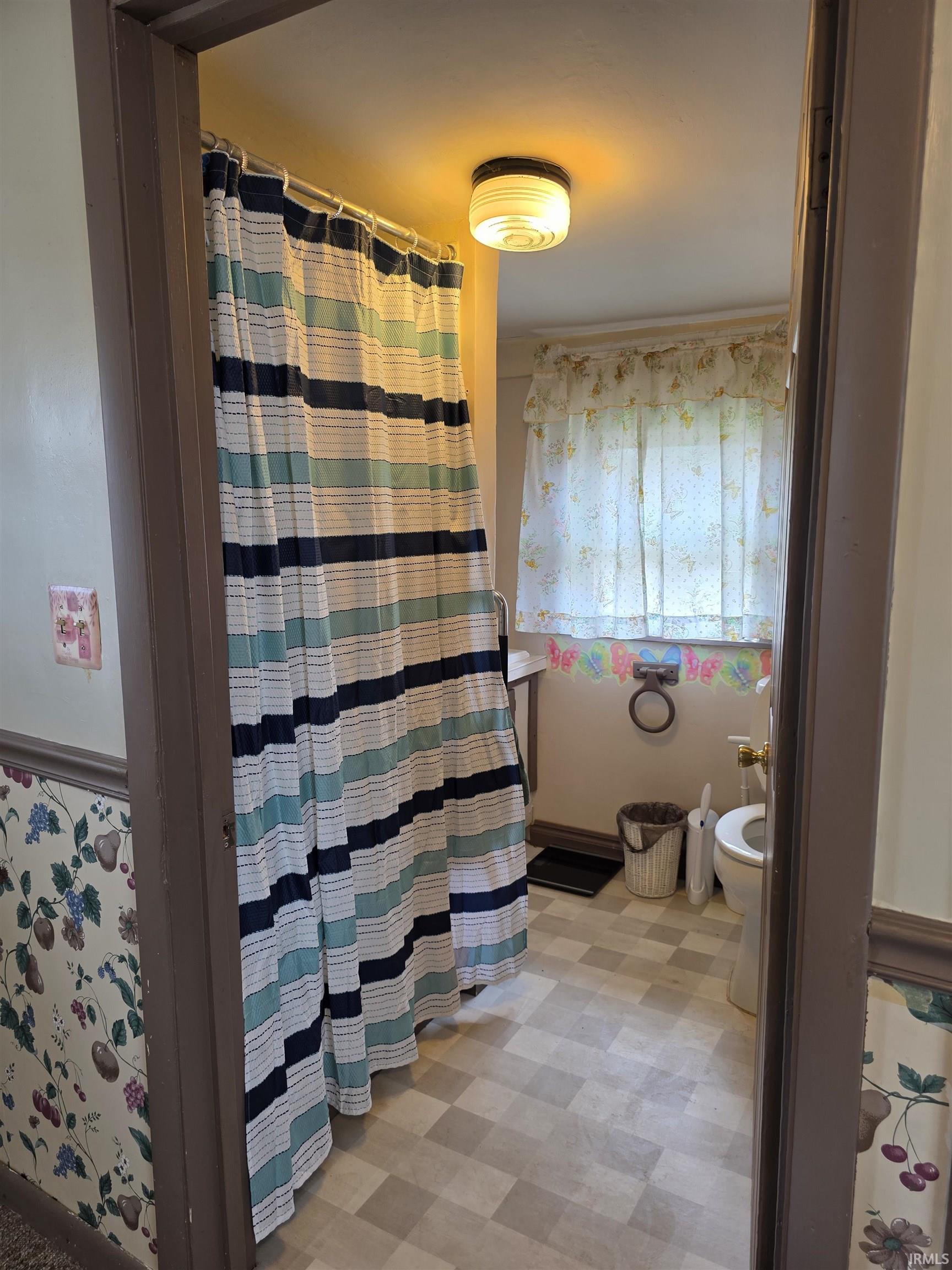 Bathroom featuring light floors and a shower with curtain