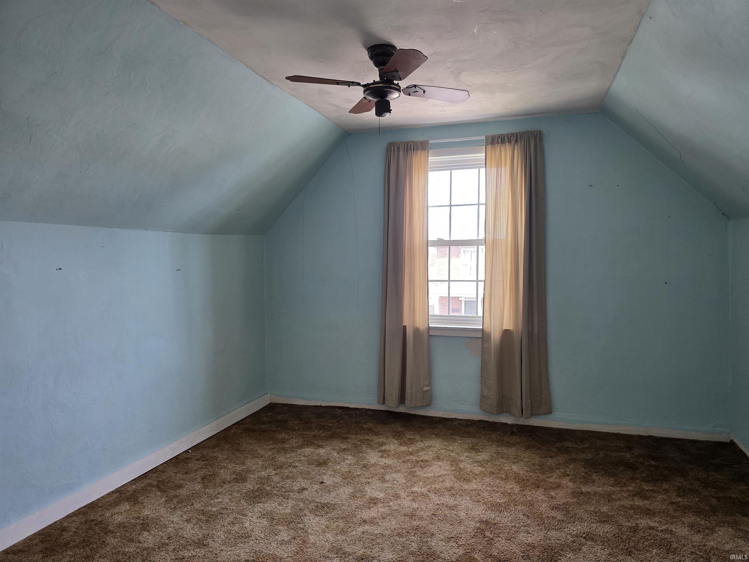 Additional living space featuring a ceiling fan and carpet