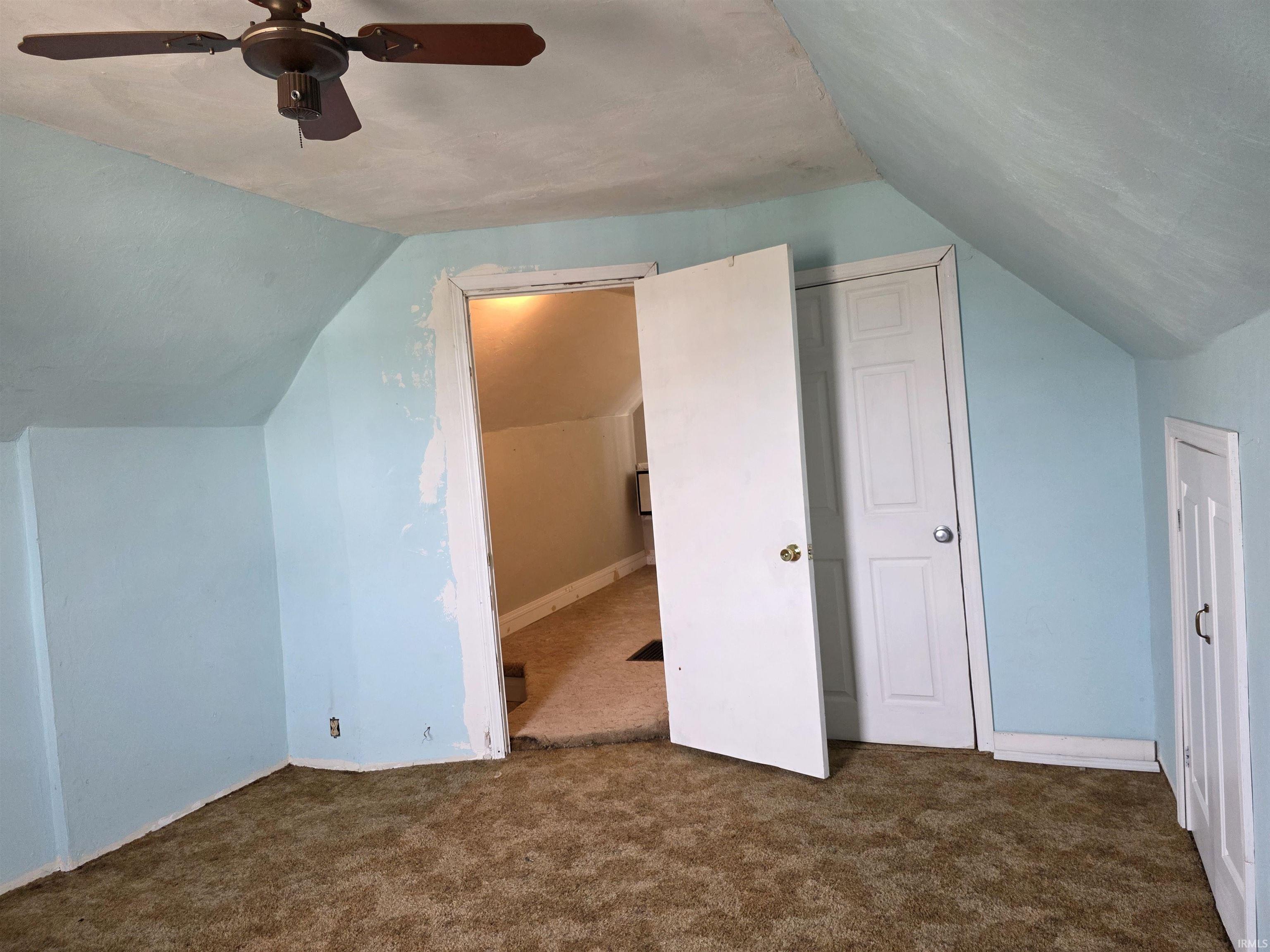 Bonus room featuring dark carpet and a ceiling fan