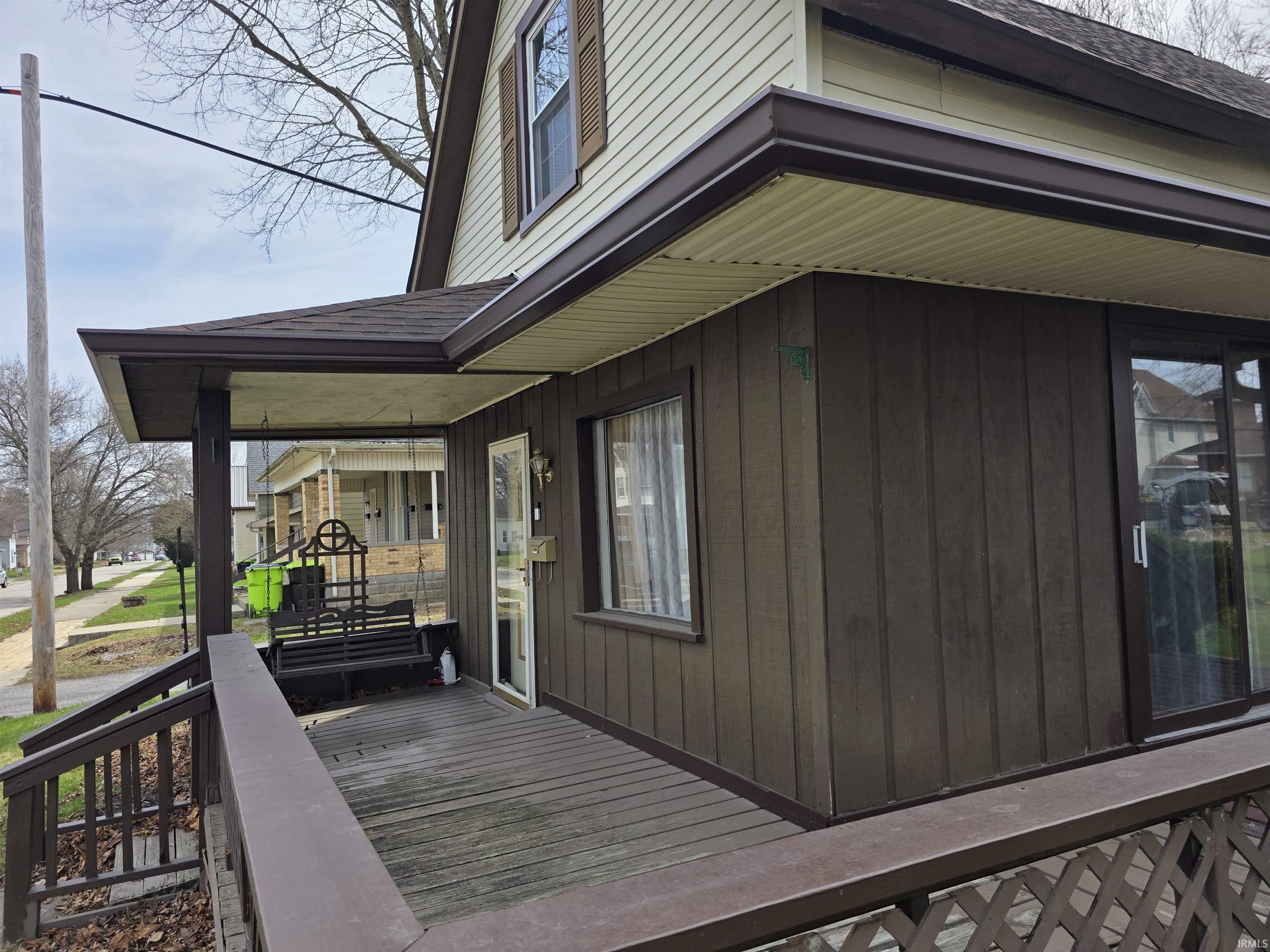 View of side of property with roof with shingles and a porch