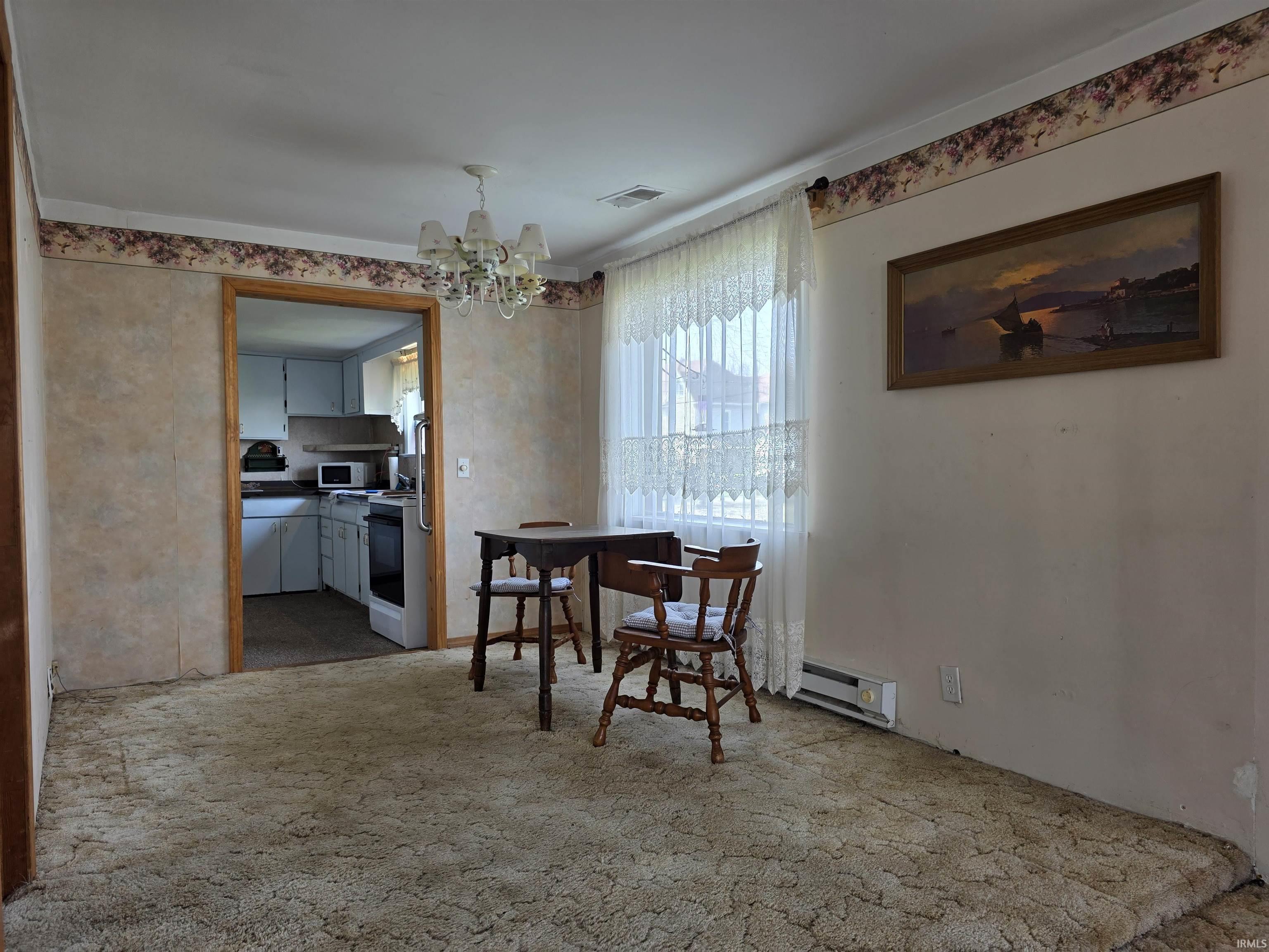 Dining area featuring light carpet, hanging lights, a baseboard heating unit, and ornamental molding