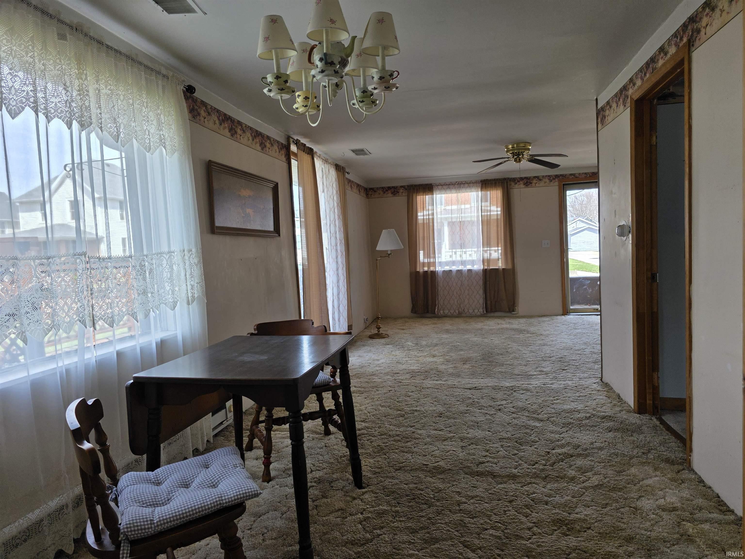 Dining space with suspended lighting, carpet, and a ceiling fan