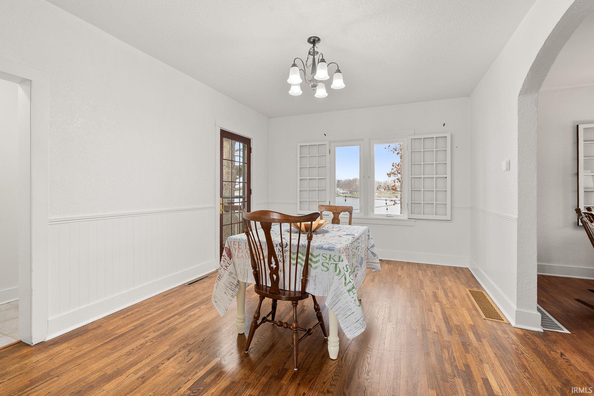 Dining area featuring arched walkways, wood finished floors, and a chandelier