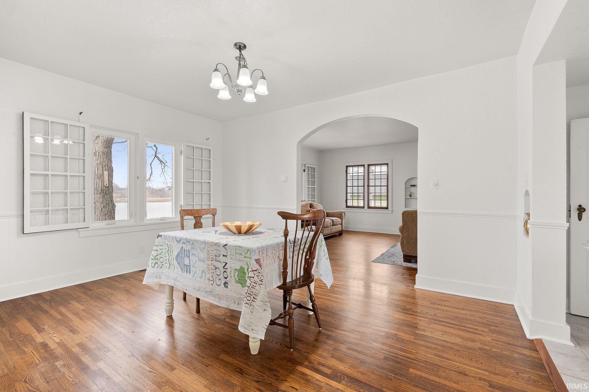Dining room with wood finished floors, arched walkways, and a chandelier