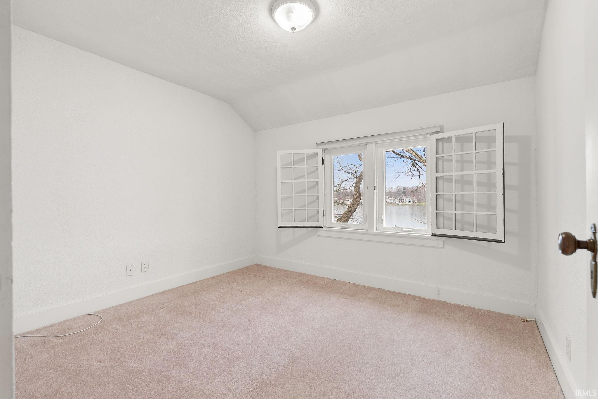 Spare room featuring light carpet and lofted ceiling