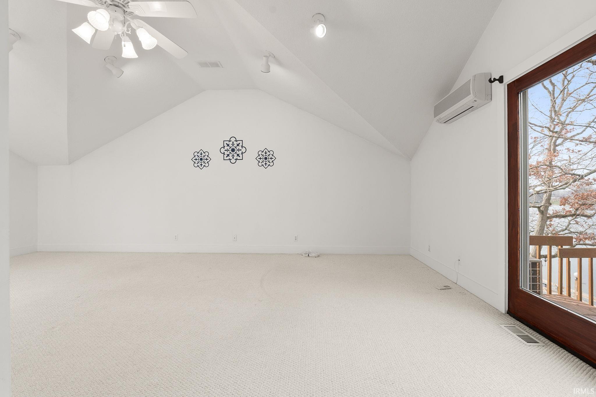 Bonus room with light colored carpet, a ceiling fan, and a wall mounted mini split