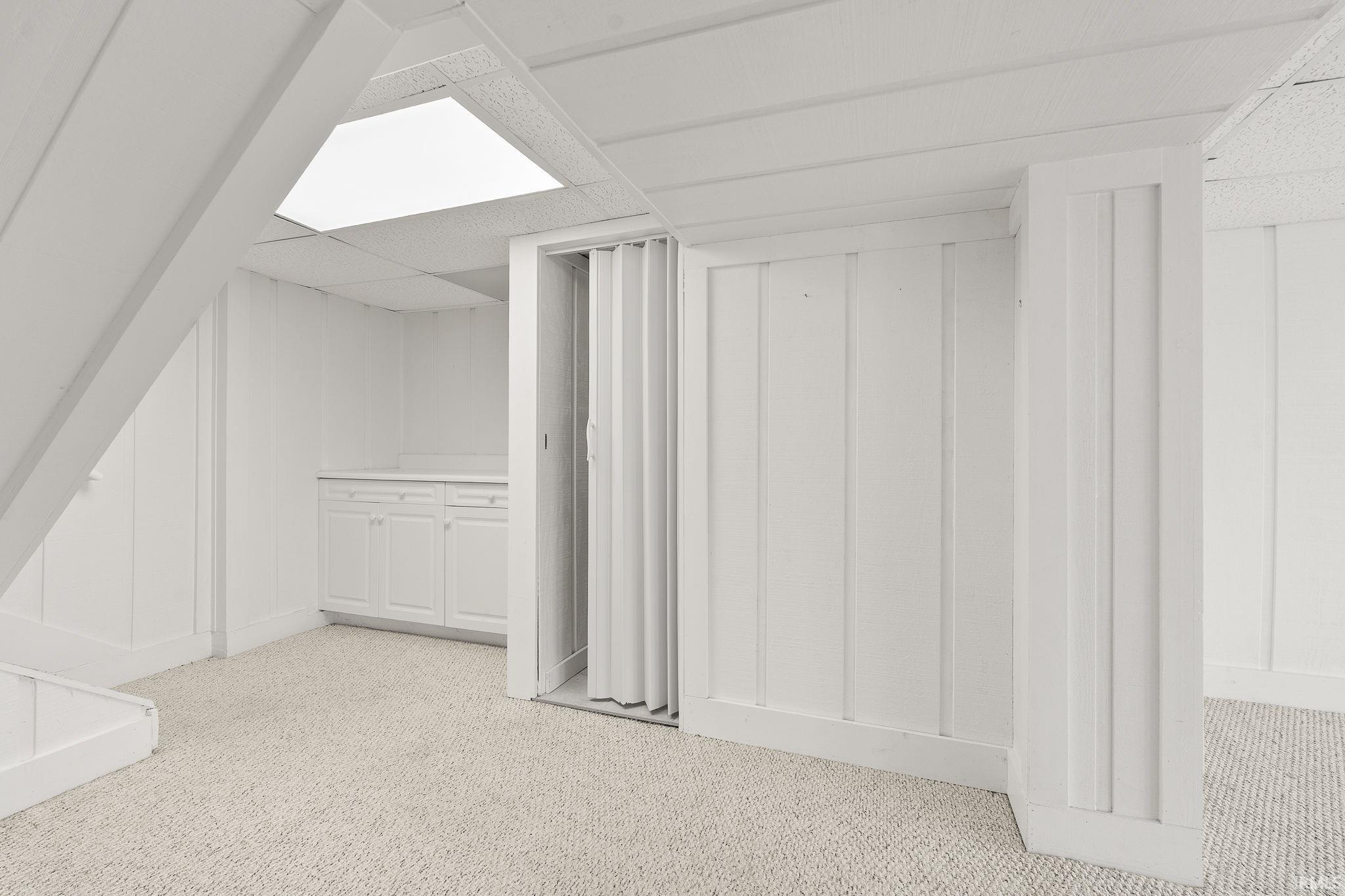 Finished below grade area with light colored carpet and a drop ceiling
