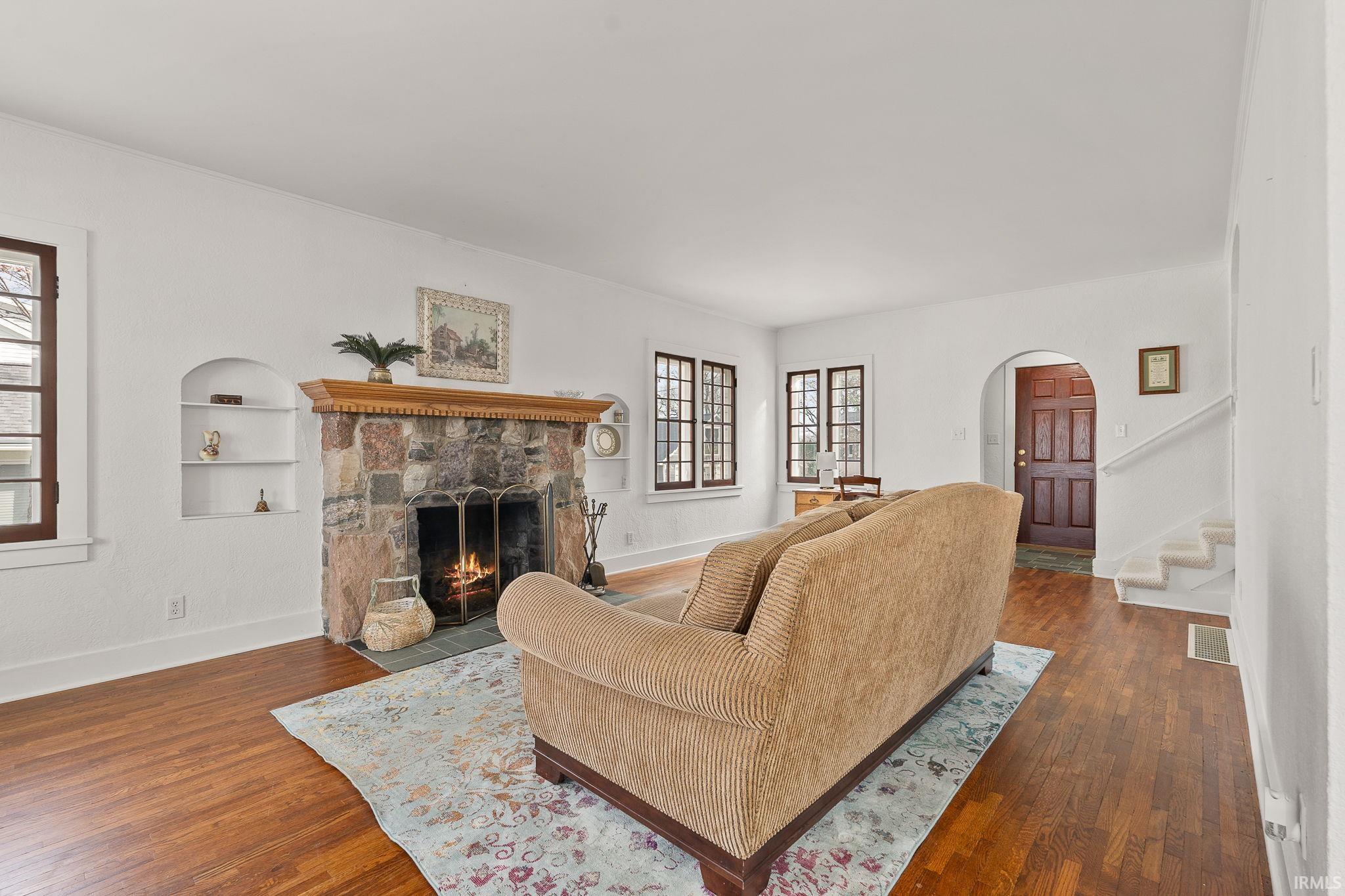 Living area featuring arched walkways, hardwood / wood-style flooring, a fireplace, and built in features
