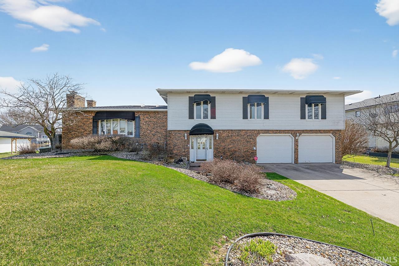 View of front of home featuring a front lawn, driveway, an attached garage, and brick siding