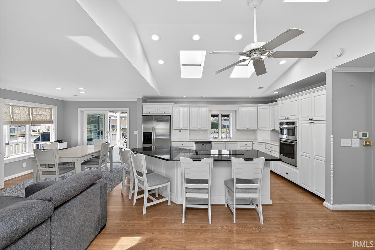 Kitchen with a kitchen bar, white cabinetry, a spacious island, a skylight, and stainless steel appliances