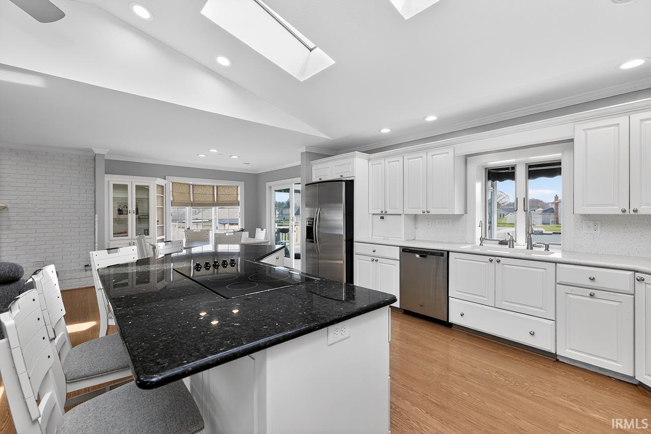 Kitchen with a kitchen island, crown molding, white cabinetry, a kitchen bar, and lofted ceiling