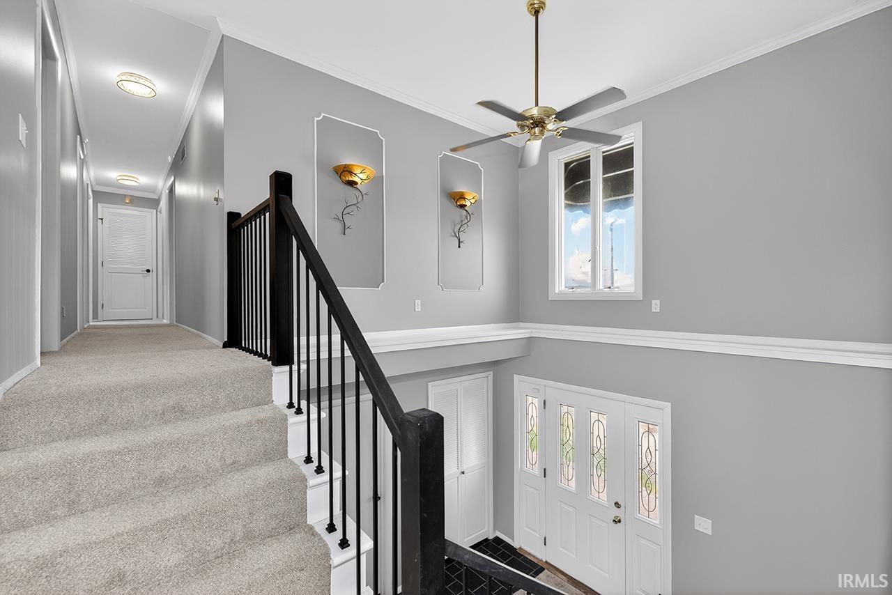Staircase featuring ornamental molding and ceiling fan