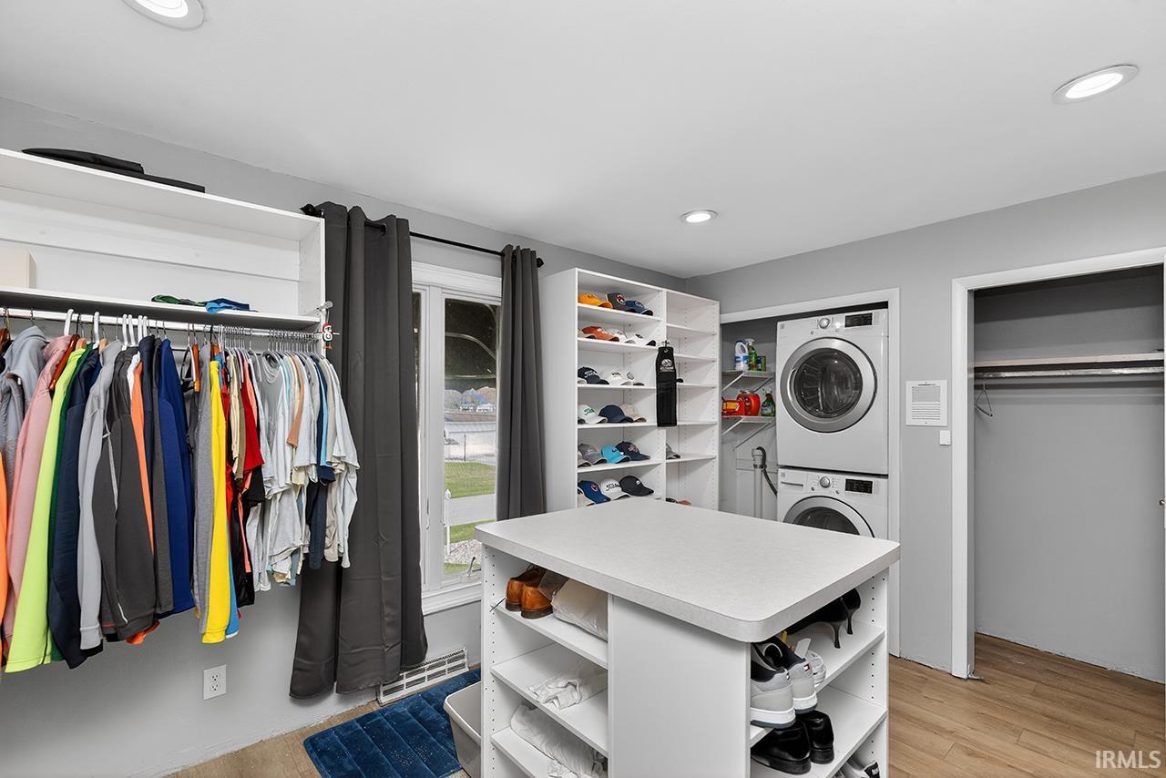 Walk in closet with light wood-style flooring and stacked washer / dryer