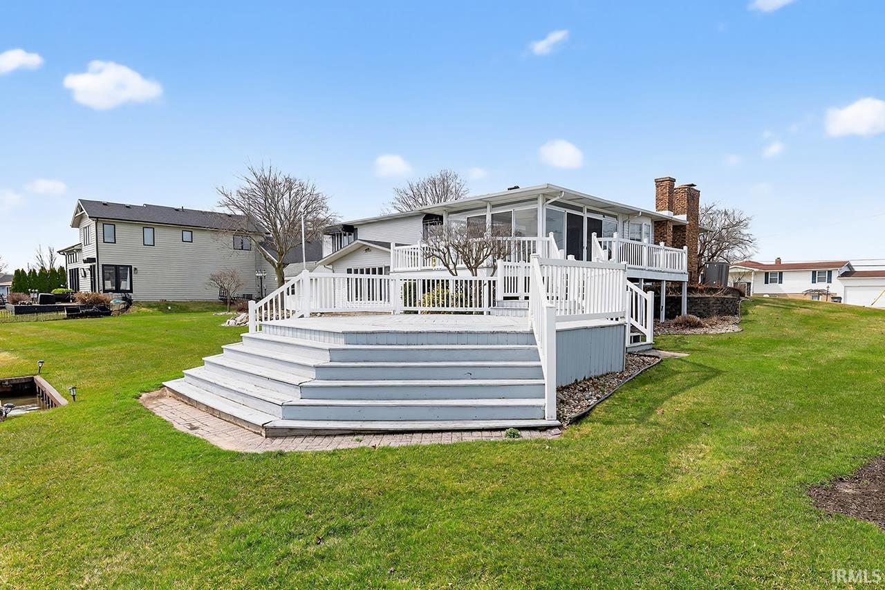 Back of property with a sunroom, a deck, a lawn, and a chimney