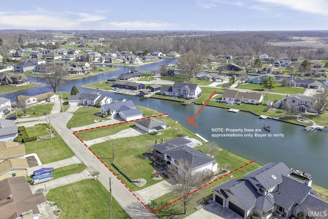 Aerial view of residential area with property boundaries highlighted and a nearby body of water