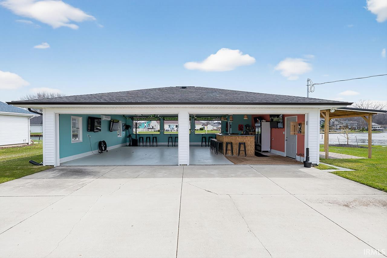 View of front of property featuring a garage, roof with shingles, driveway, and a front yard