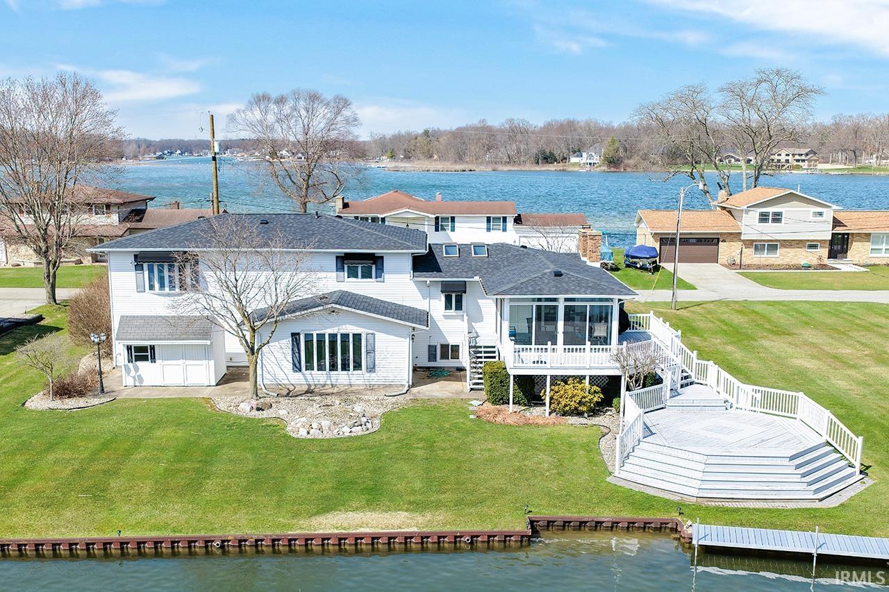 Rear view of house with a water view, a sunroom, a lawn, and a patio area