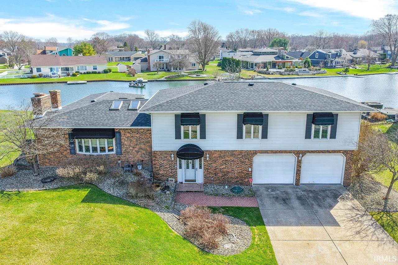 Traditional-style house with driveway, an attached garage, a front yard, and a shingled roof