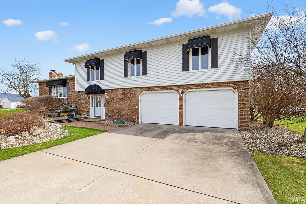 Split level home featuring concrete driveway, a garage, and brick siding