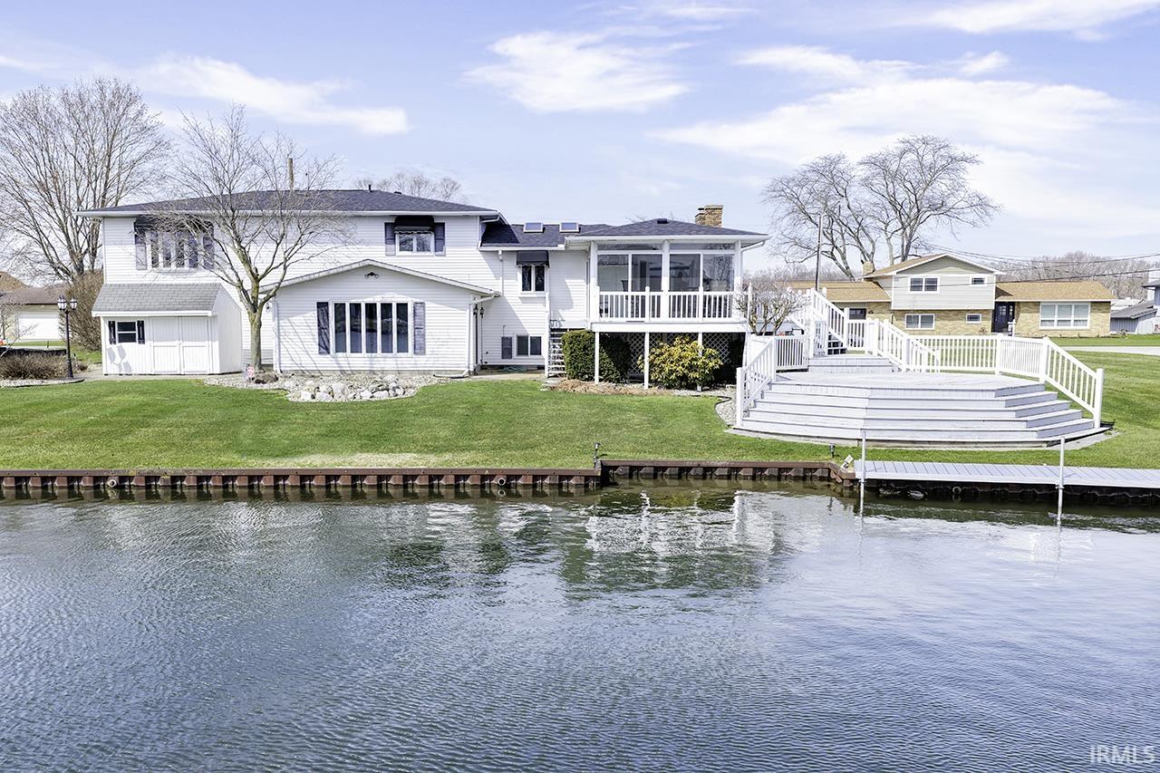 Back of property featuring a sunroom, a water view, a chimney, and a yard