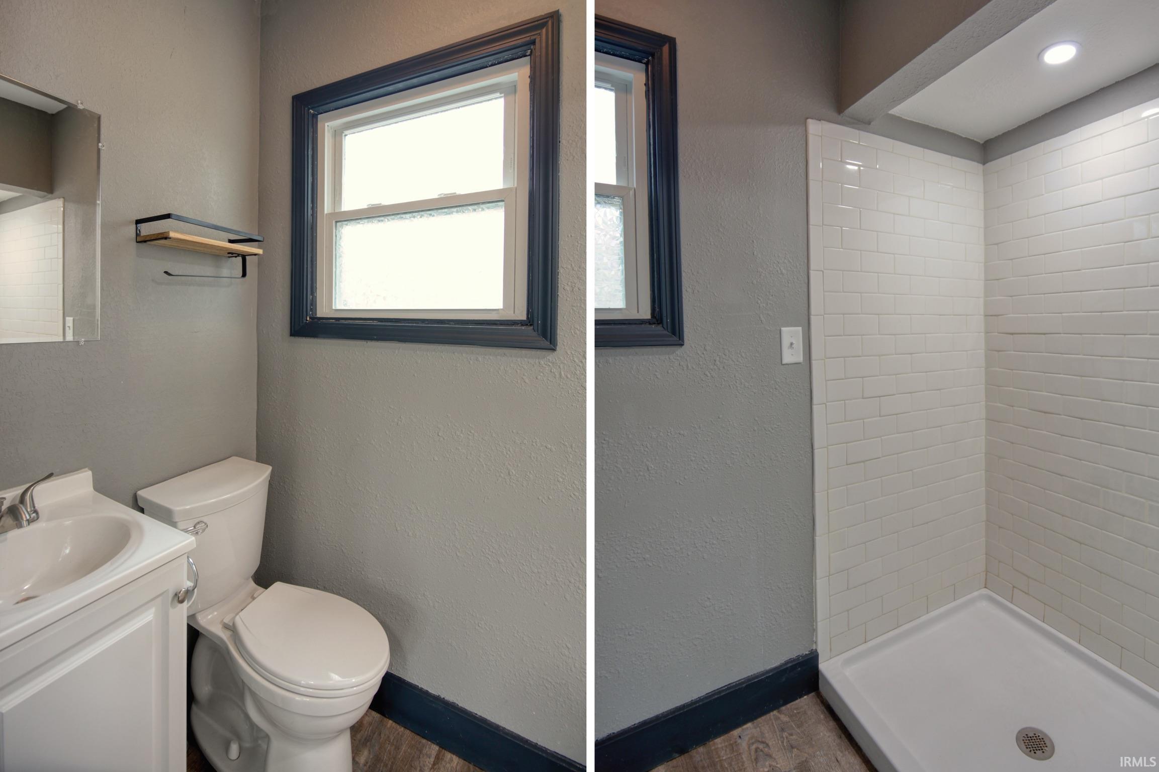 Full bath featuring vanity, a shower stall, a textured wall, and dark wood-style floors