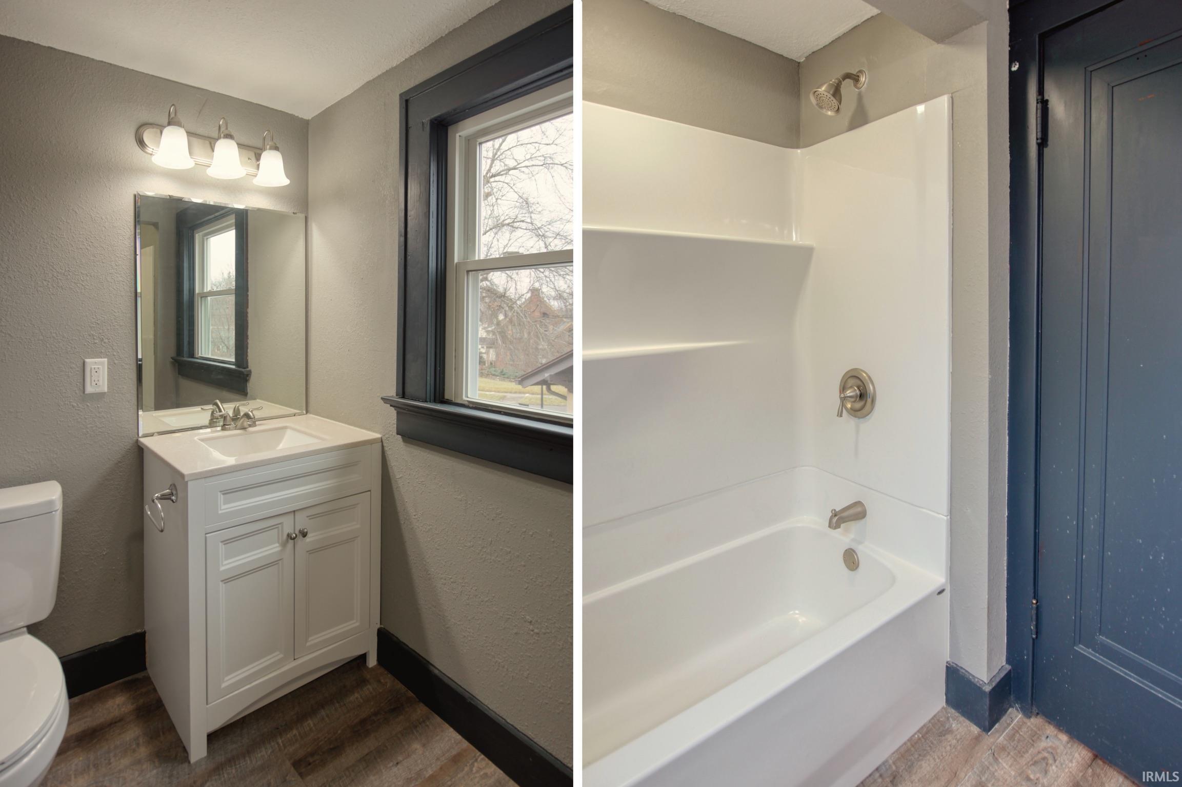 Full bath featuring a textured wall, dark wood-style flooring, bathtub / shower combination, and vanity
