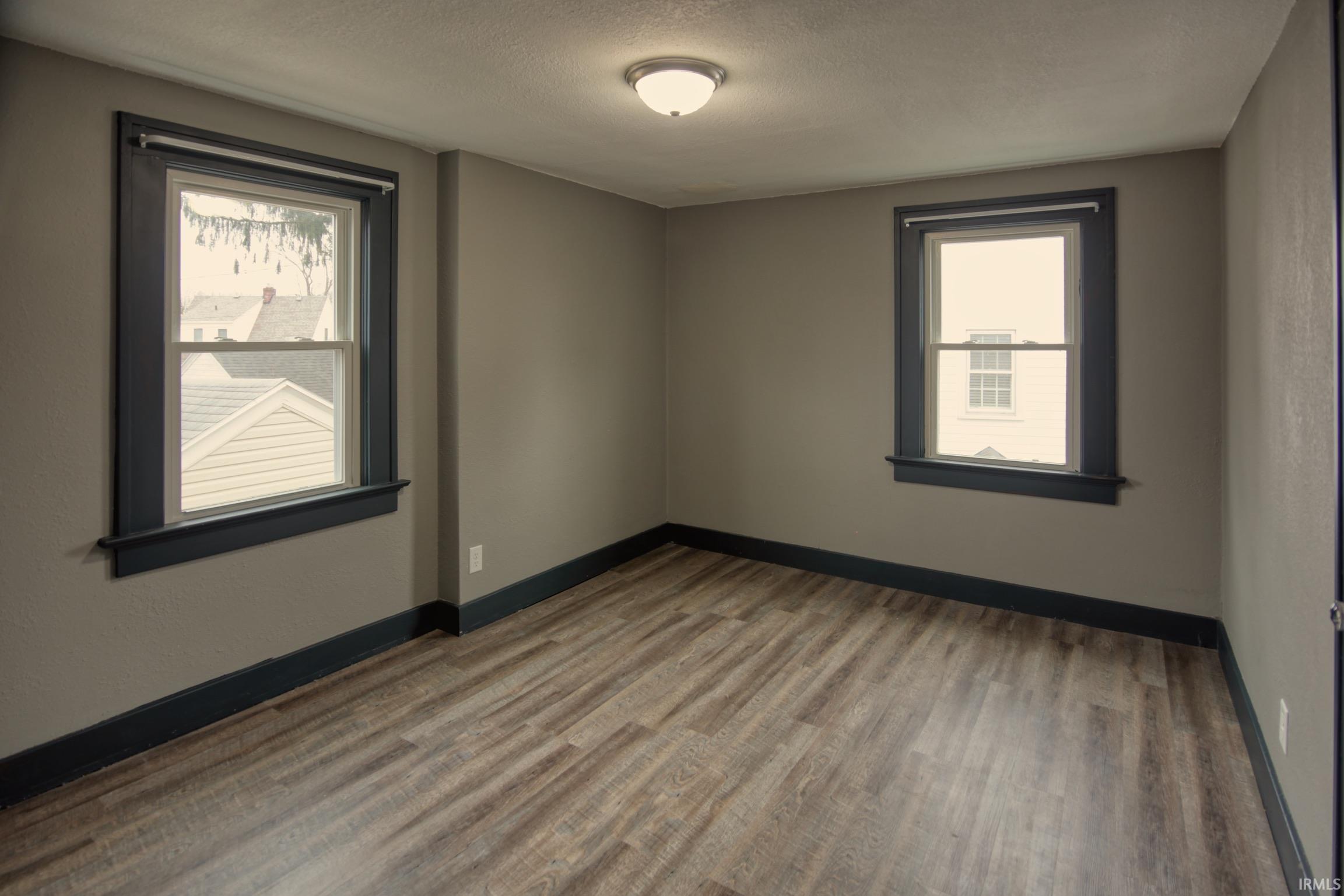 Empty room featuring wood finished floors, a textured ceiling, and healthy amount of natural light