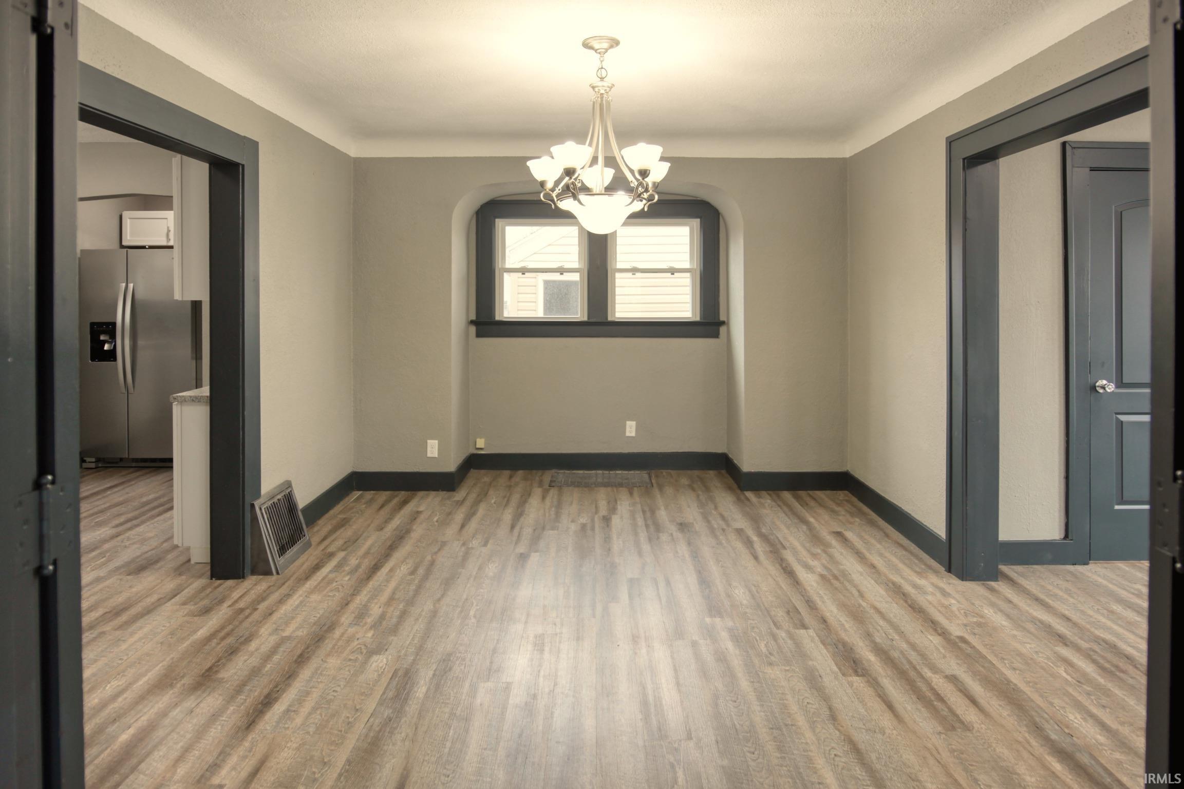 Unfurnished room with a chandelier, light wood-style floors, and a barn door