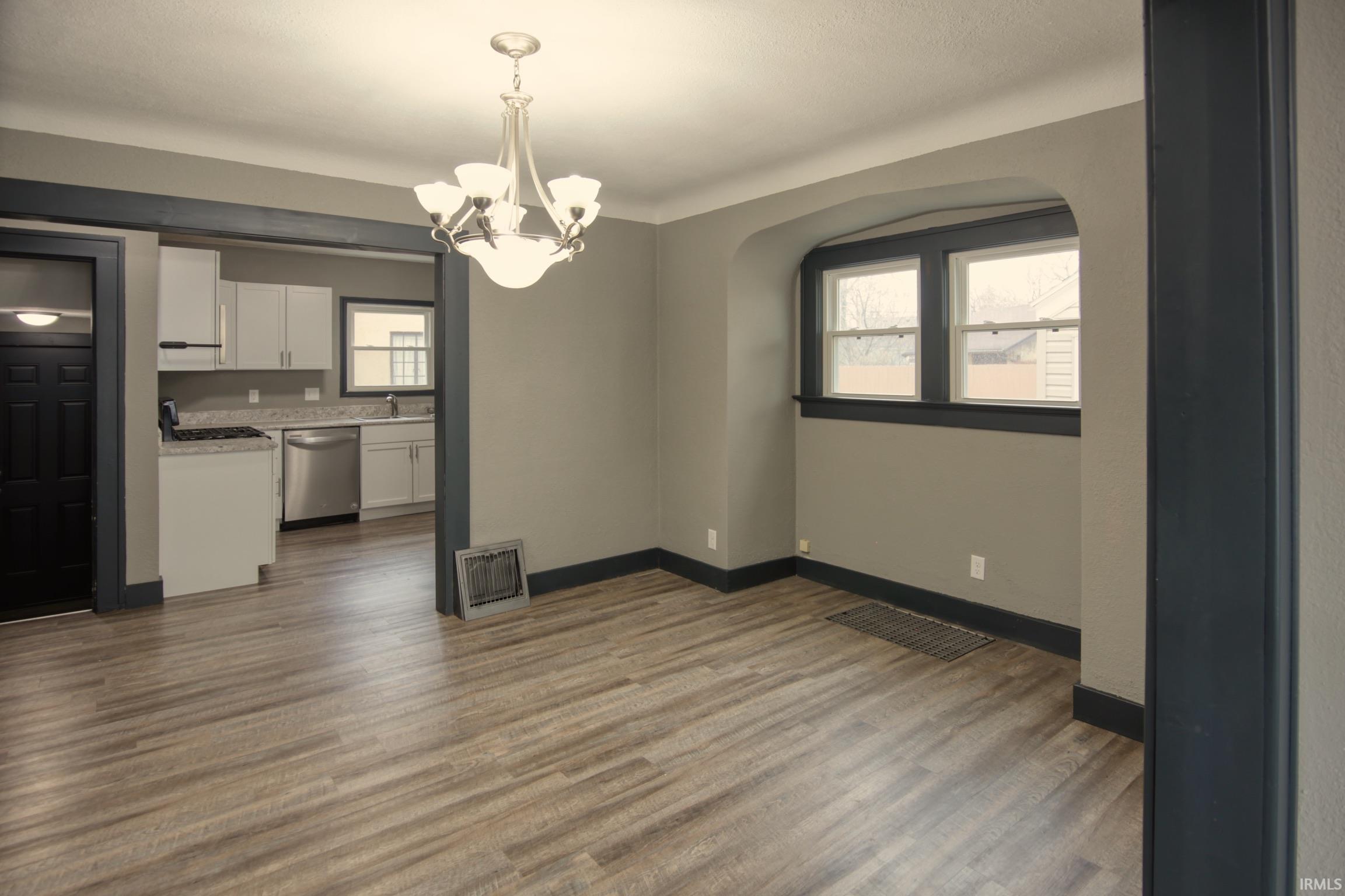 Unfurnished dining area featuring a chandelier and dark wood-style floors