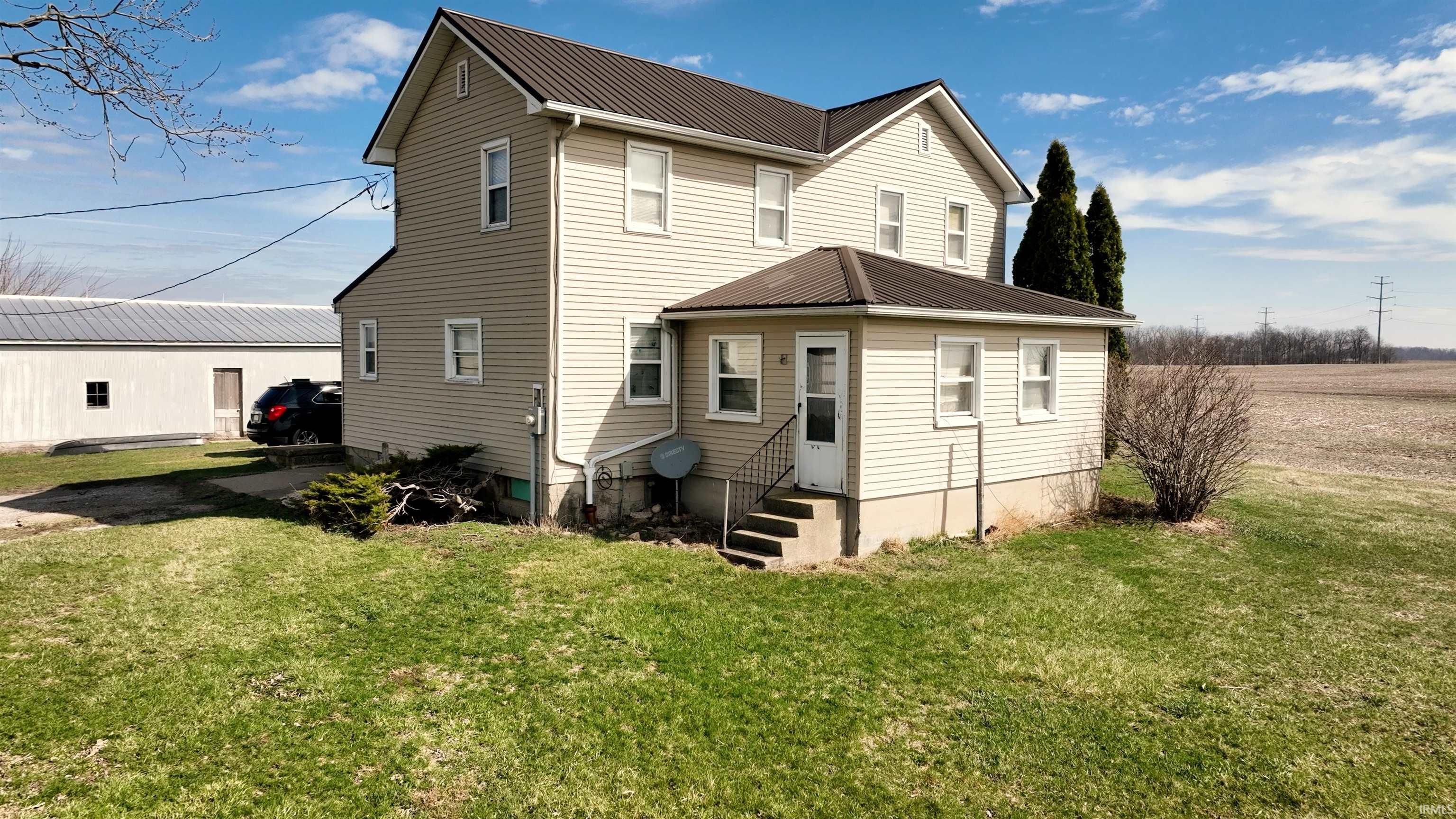 Back of house featuring a lawn, a metal roof, and entry steps