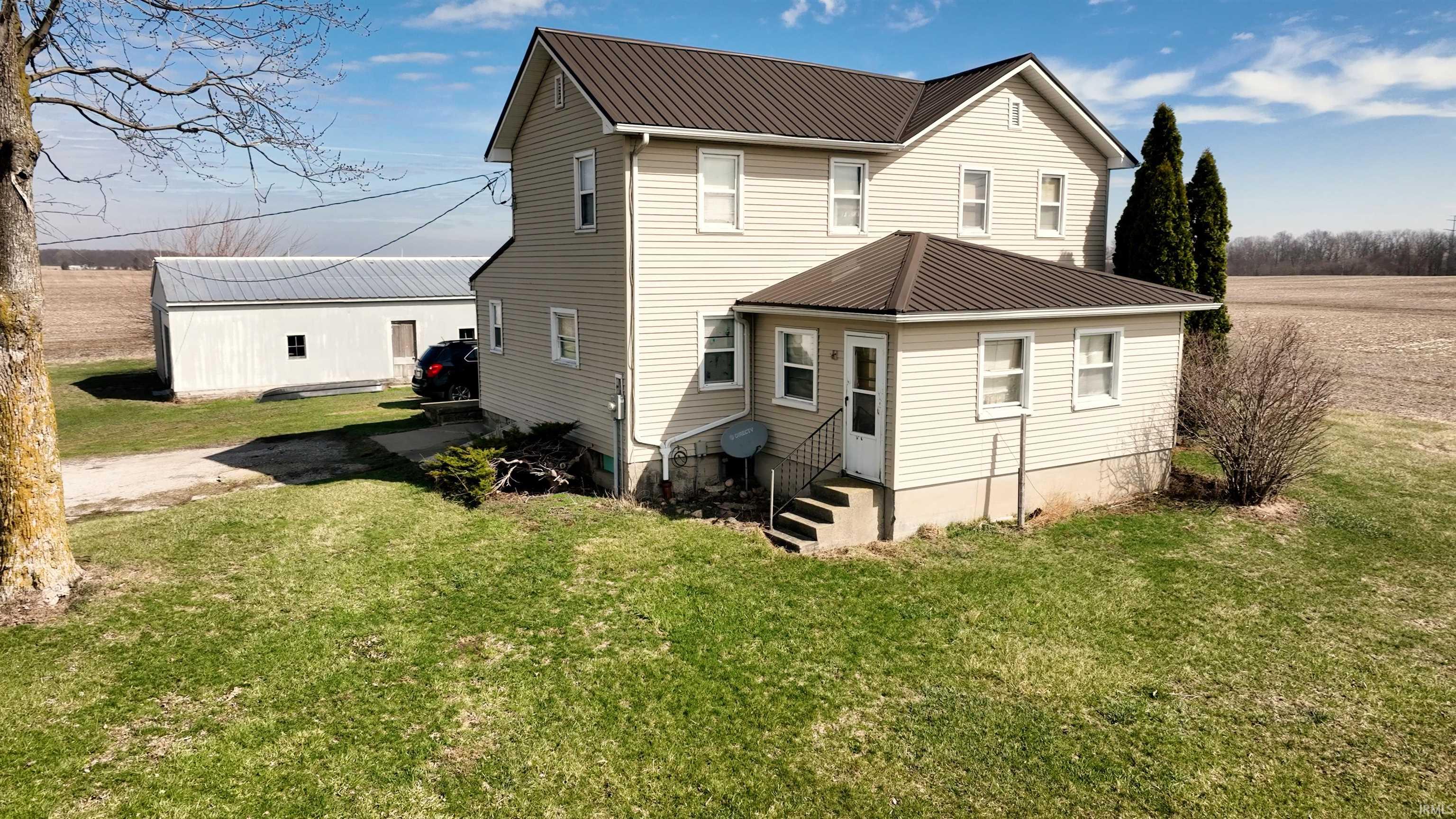 Rear view of property with entry steps, a metal roof, and a lawn