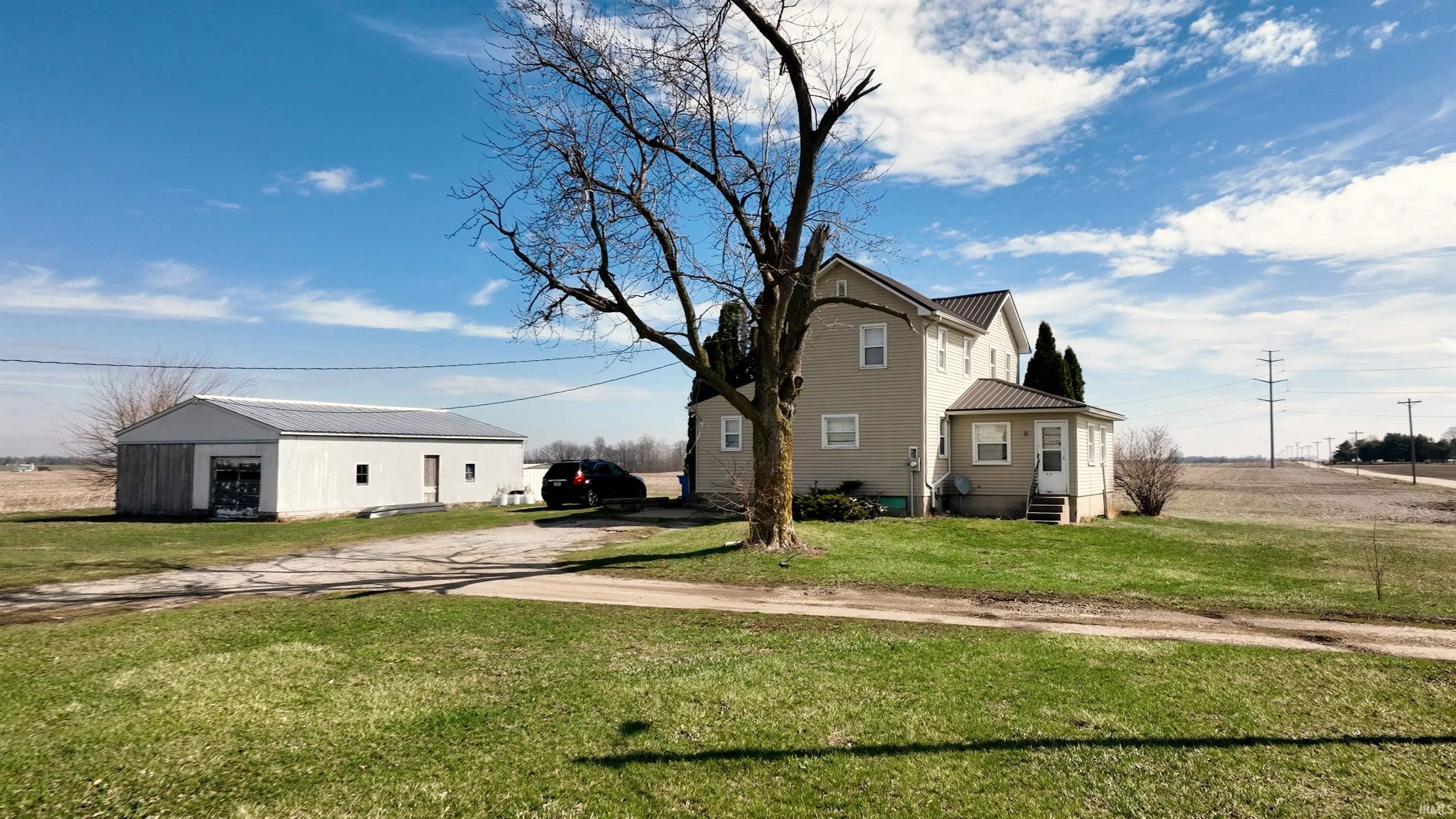 View of property exterior featuring an outdoor structure, a lawn, entry steps, a metal roof, and driveway