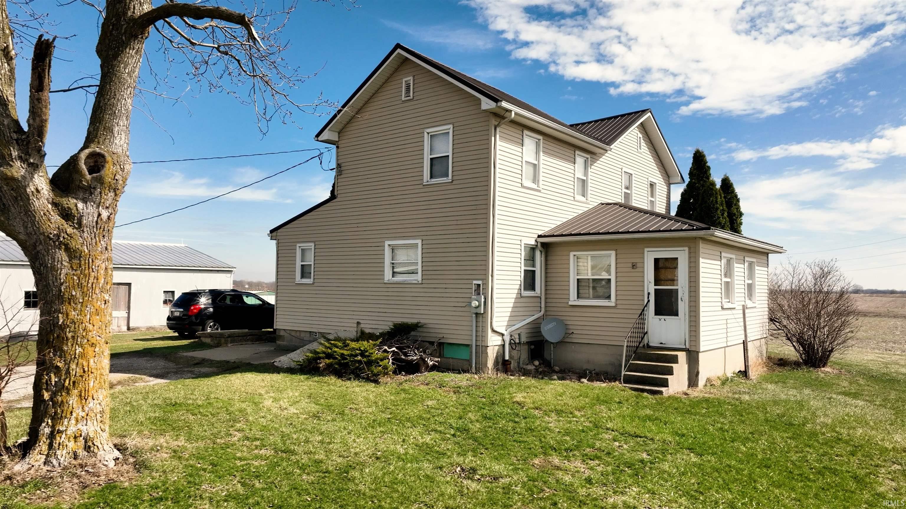 Rear view of property with entry steps, a yard, and a metal roof