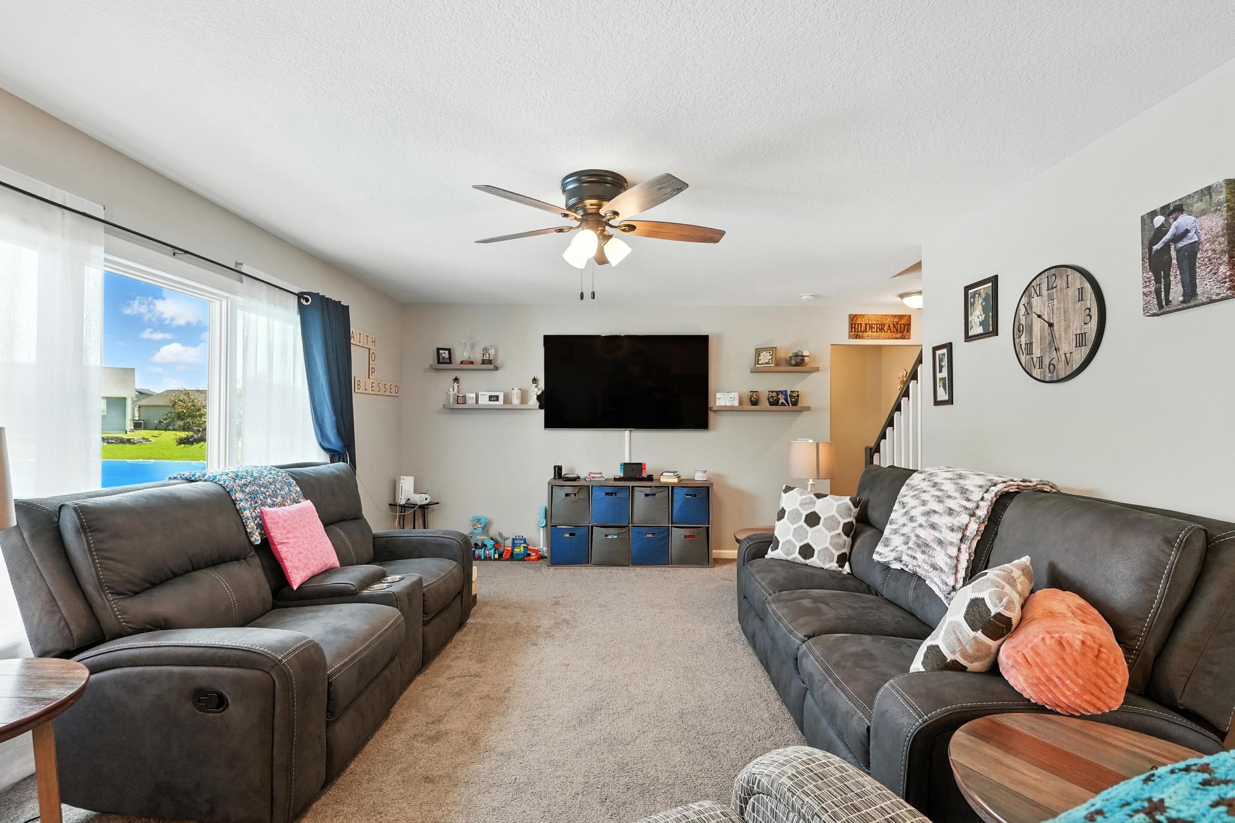 Living area featuring carpet, a ceiling fan, and a textured ceiling