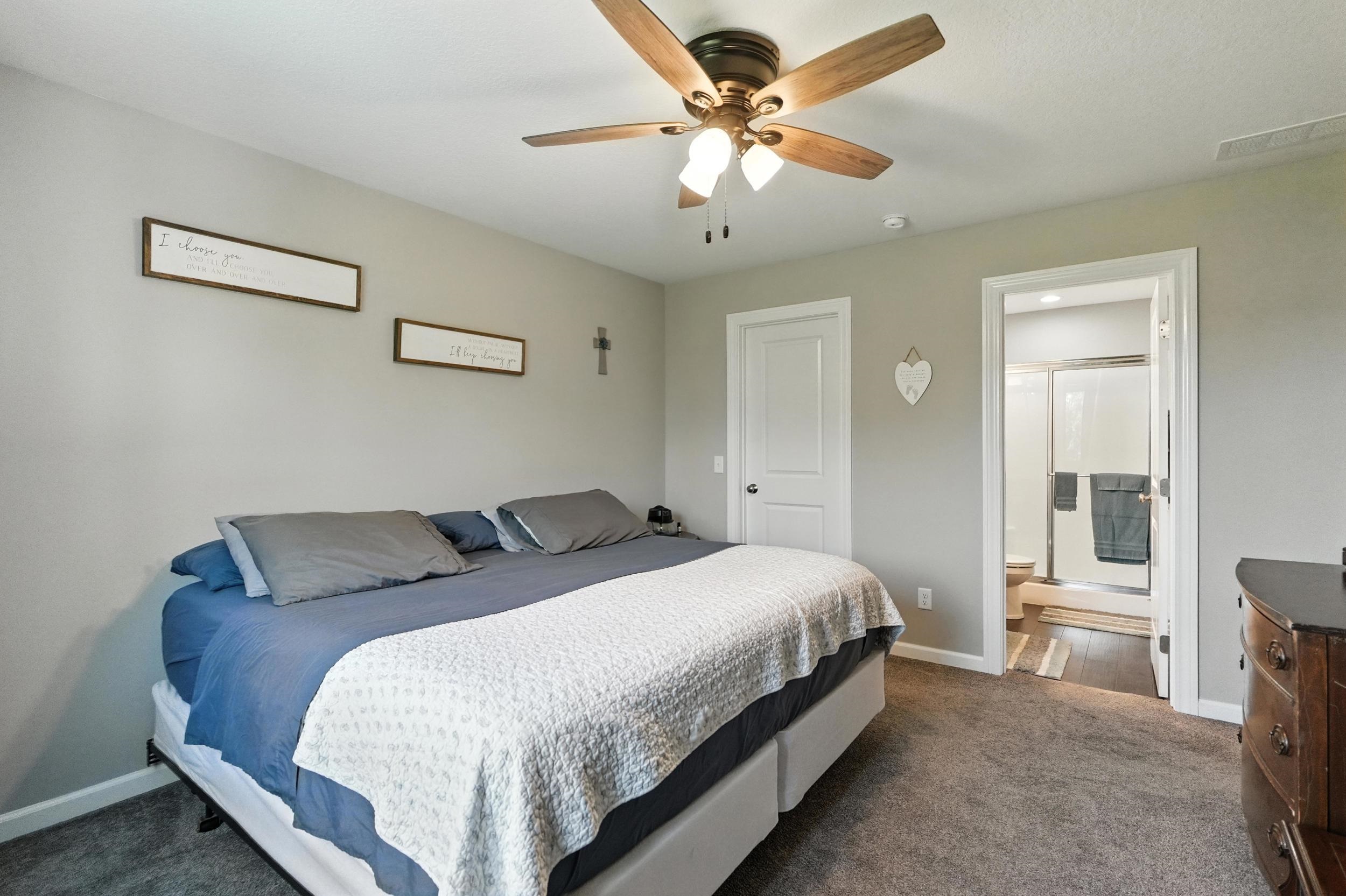 Bedroom with dark colored carpet and a ceiling fan