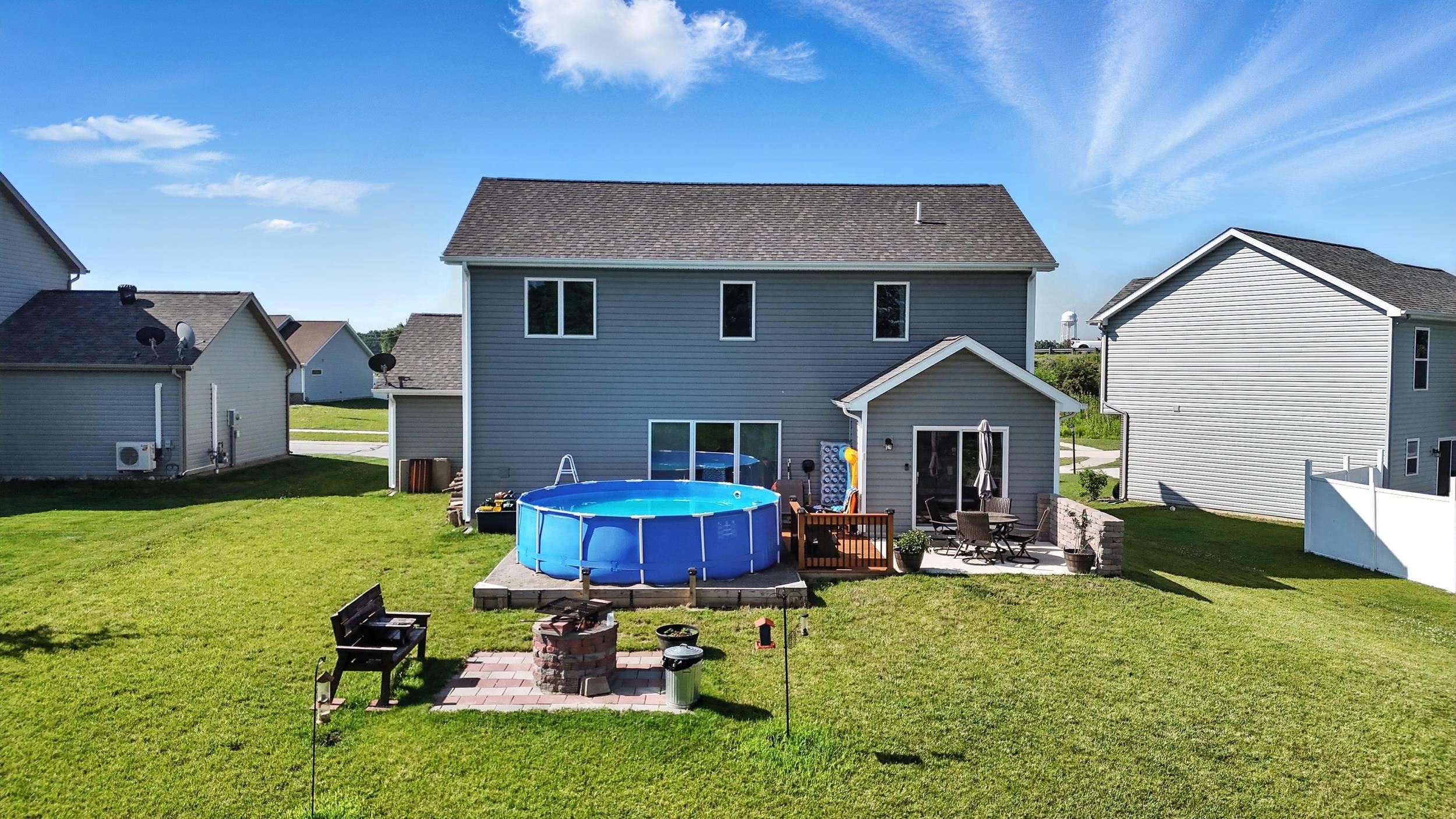 Back of property with a yard, a patio, an outdoor pool, a fire pit, and a shingled roof