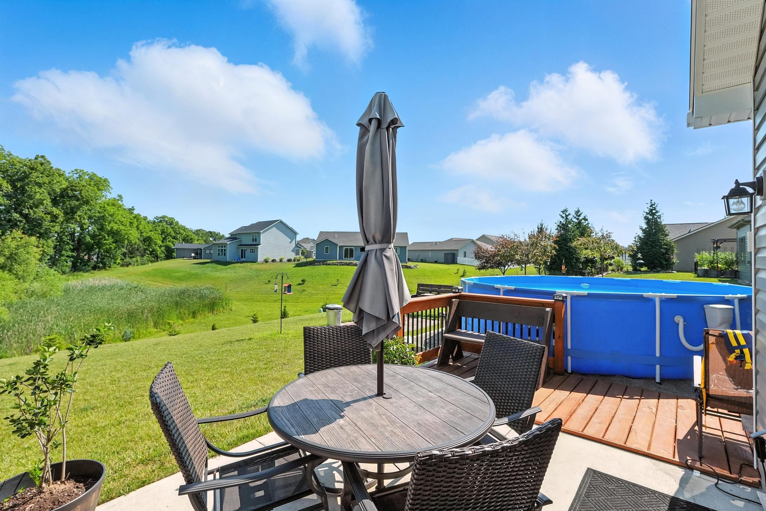 Wooden terrace featuring outdoor dining space, an outdoor pool, a lawn, and a residential view