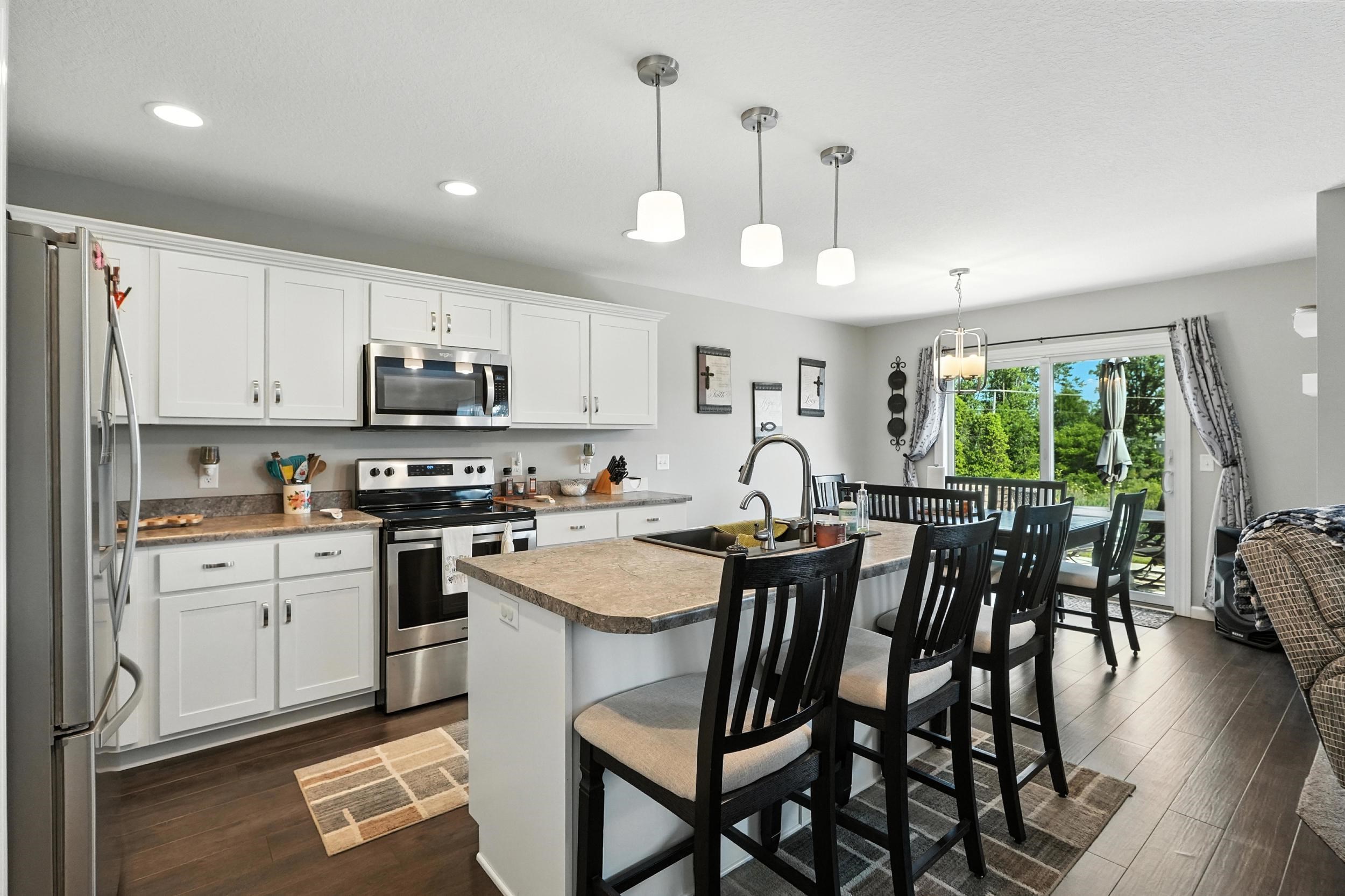 Kitchen featuring white cabinetry, stainless steel appliances, a kitchen island with sink, a kitchen bar, and dark wood-style floors