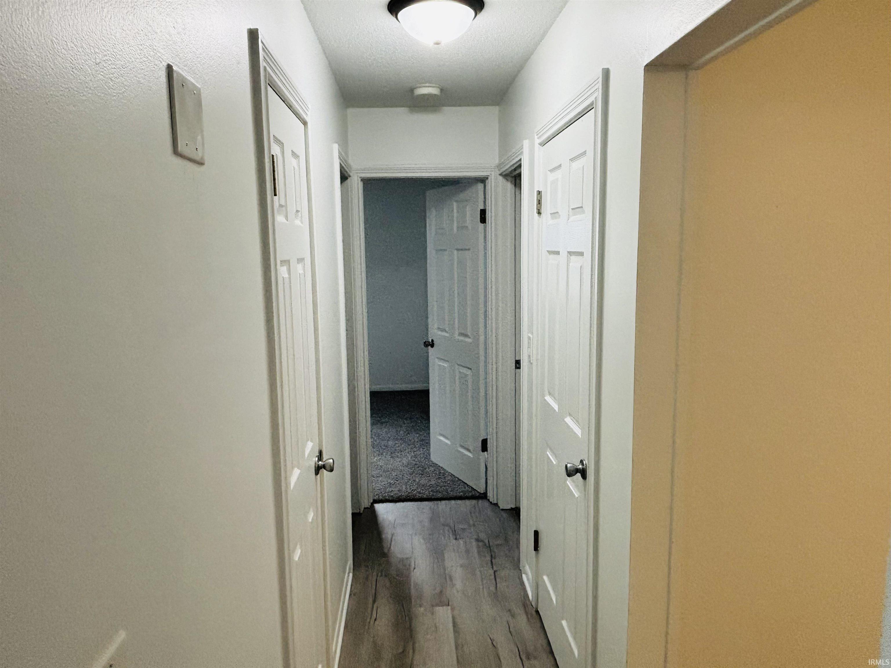 Hall with dark wood-type flooring and baseboards