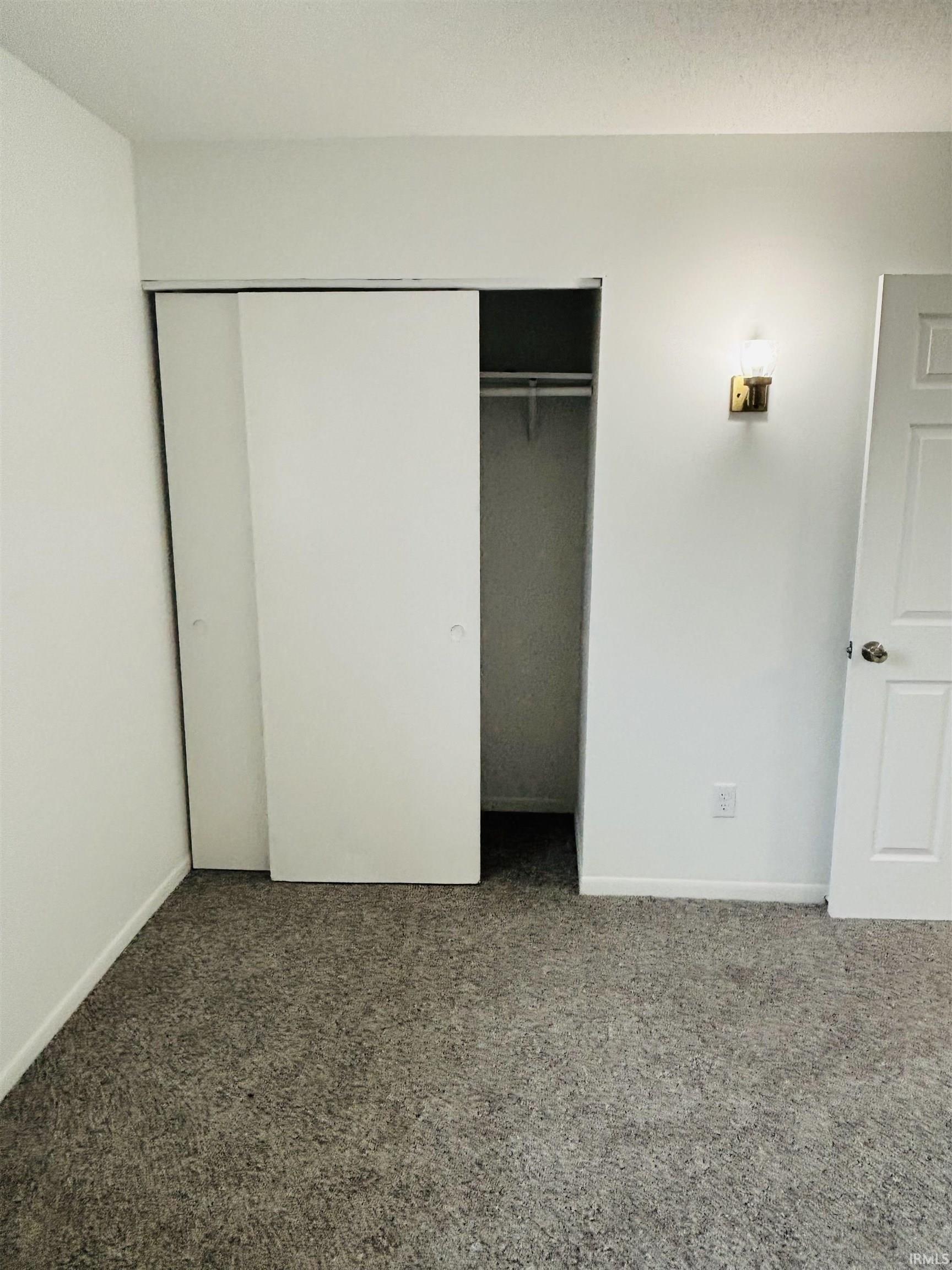 Unfurnished bedroom featuring dark colored carpet and a closet